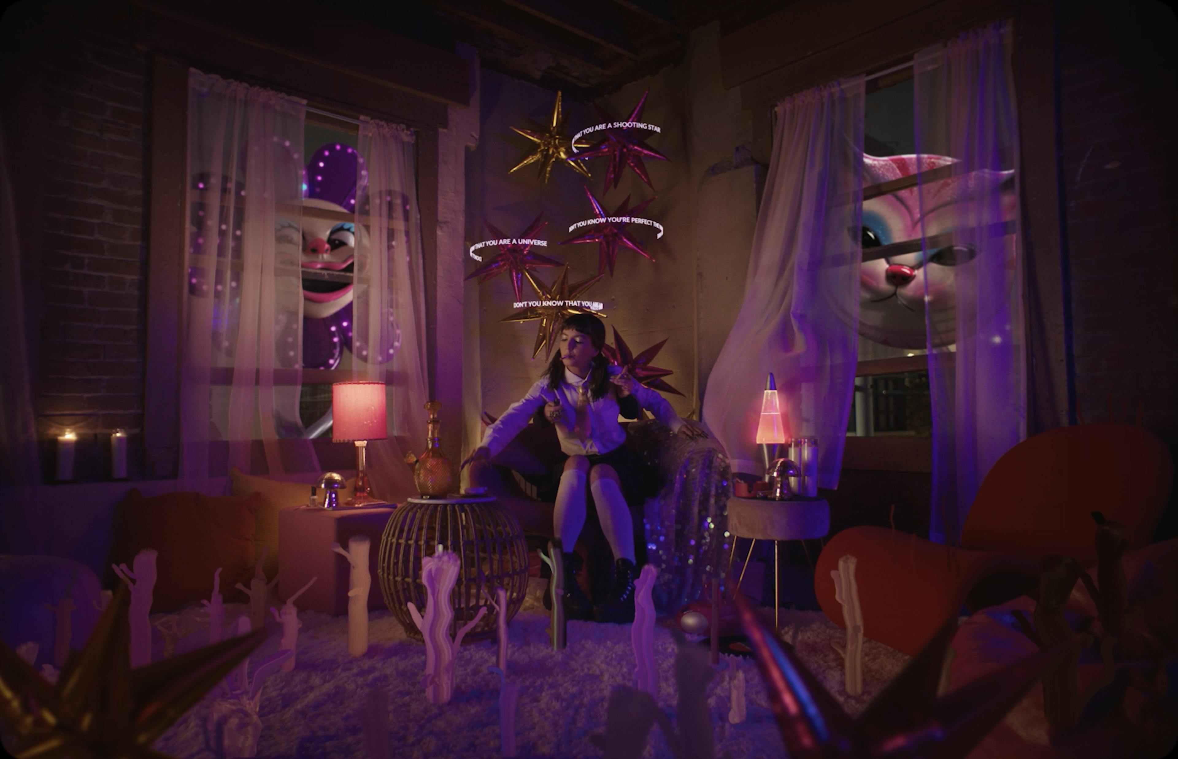 A woman sits in a room with candles and an animated flower and cat outside the window