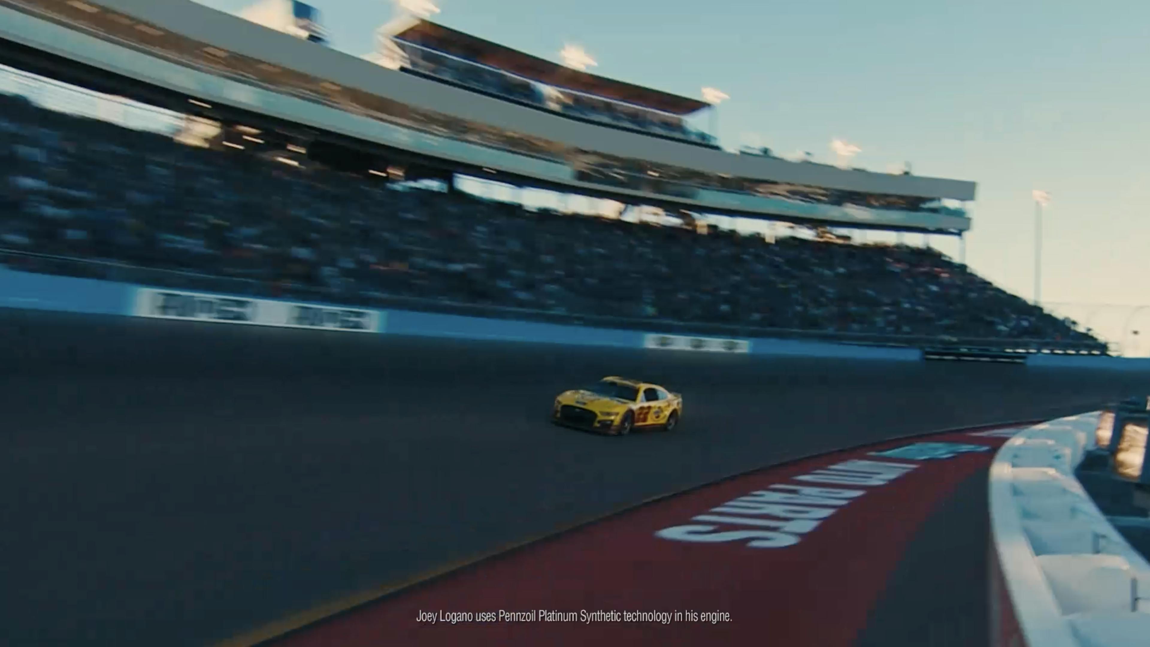 A racecar zooms down the track with the background and arena blurred