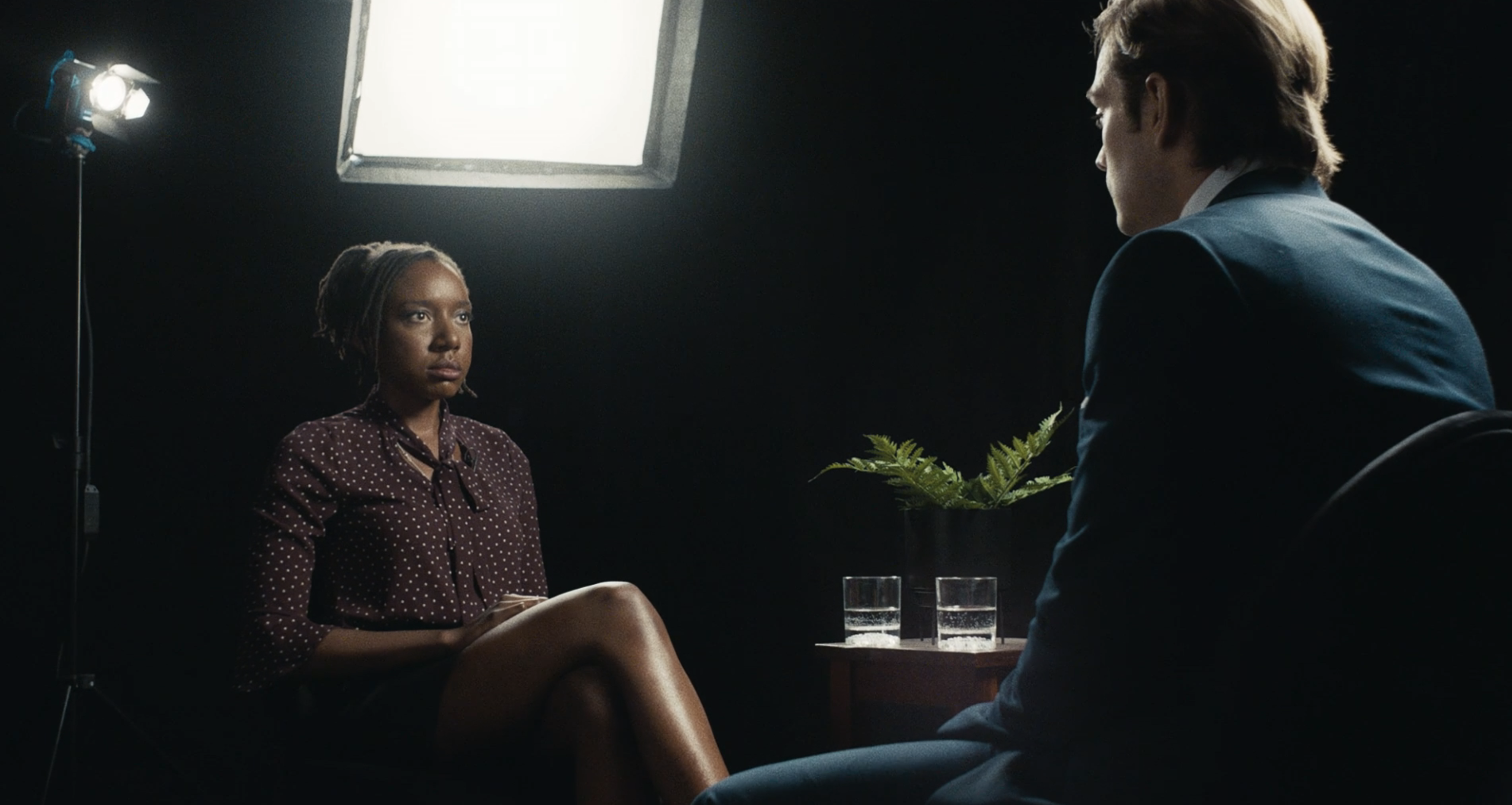 A woman in business attire sits facing a man in a suit