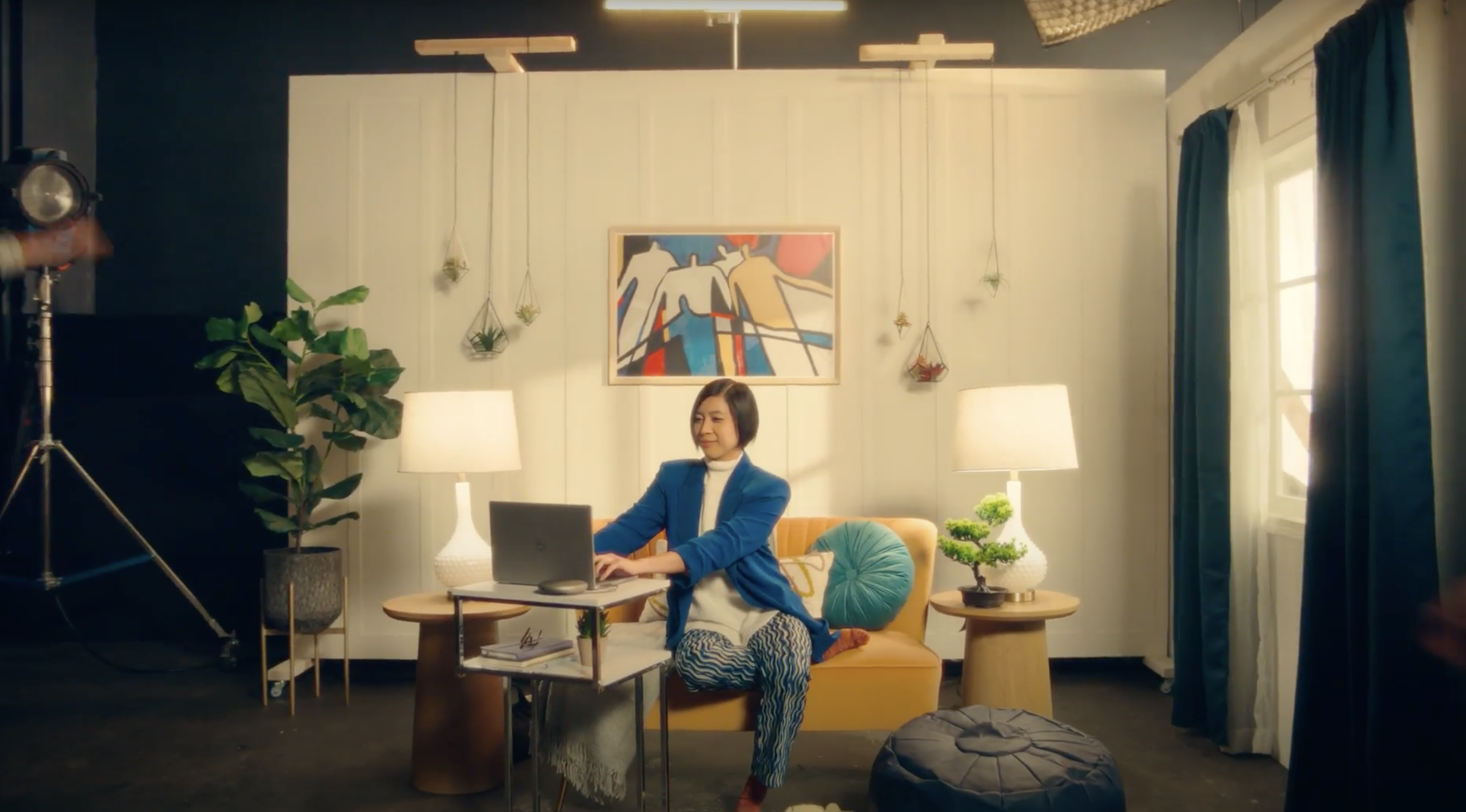 A woman sits on her couch working on her laptop
