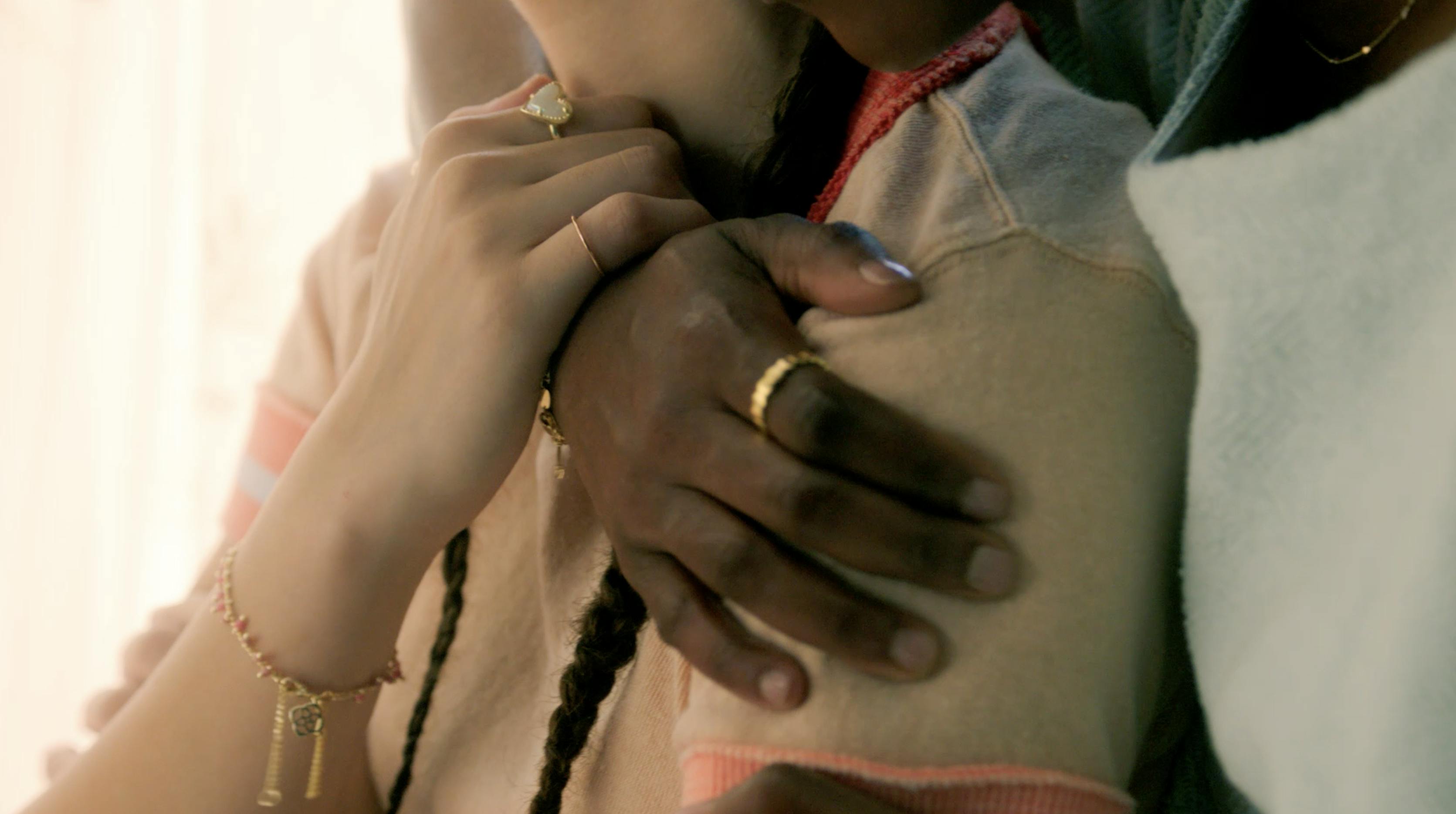 A couple's hands with rings are shown hugging each other