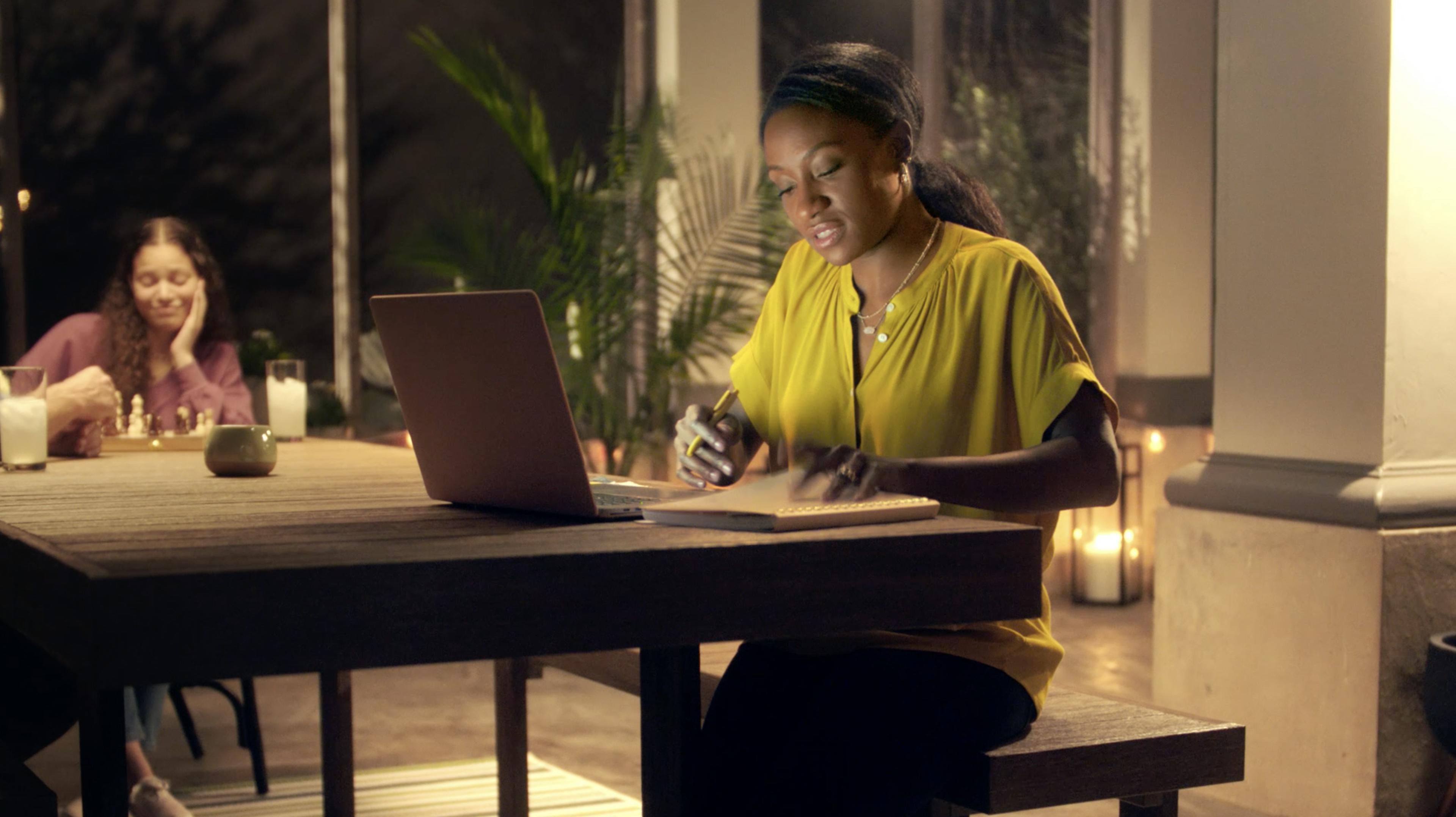 A woman works on her laptop in a candlelit space