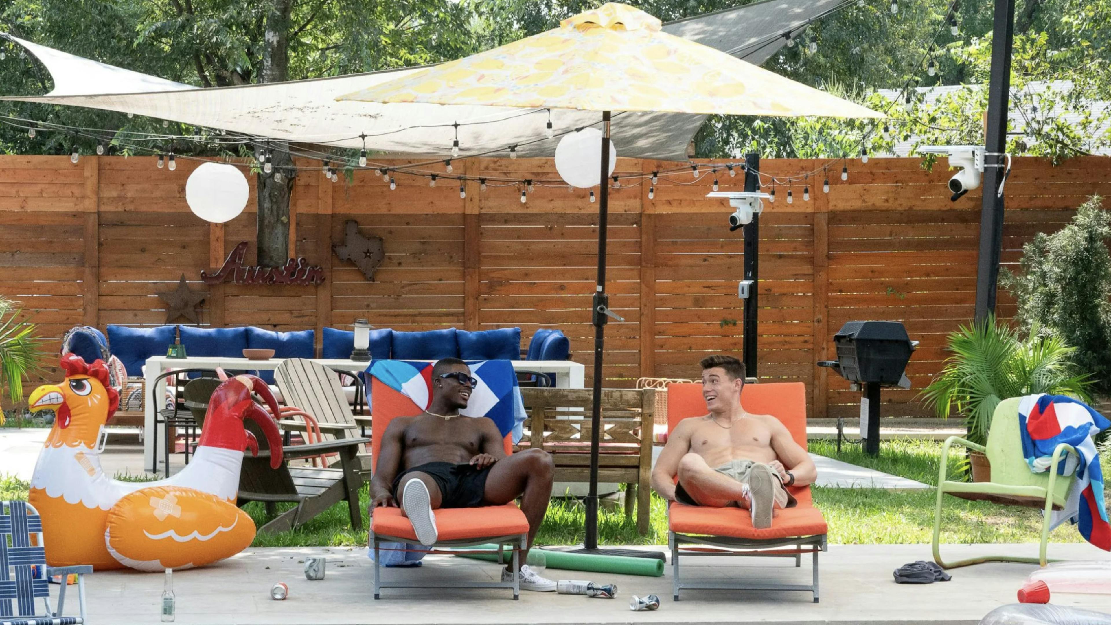 Two men sit on lounge chairs in front of a pool