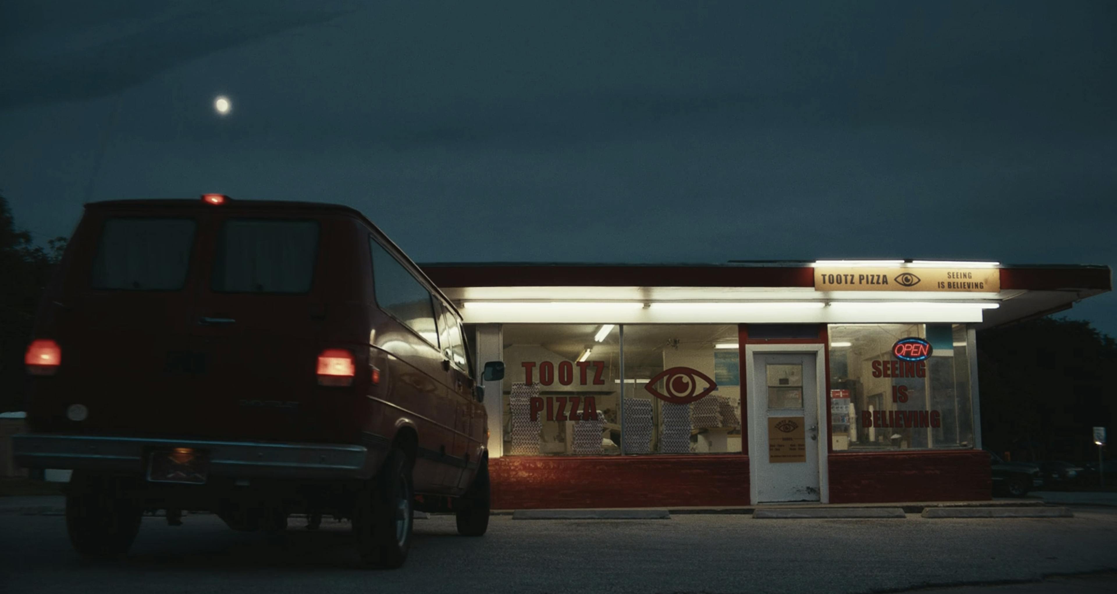 A red van in front of a pizza shop