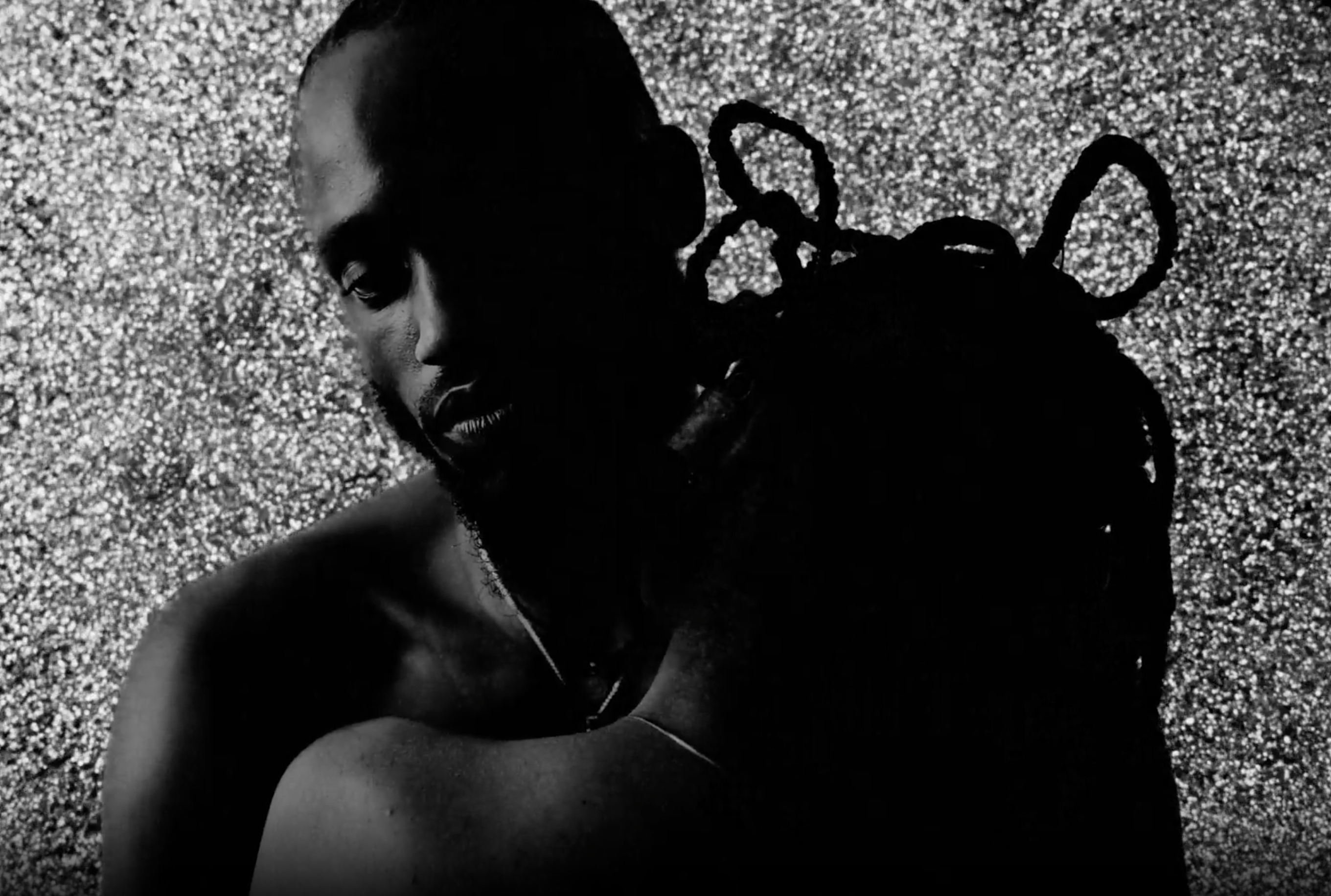 A close-up of a man and woman embracing each other, with the man's facing the camera and the woman with her back to the camera