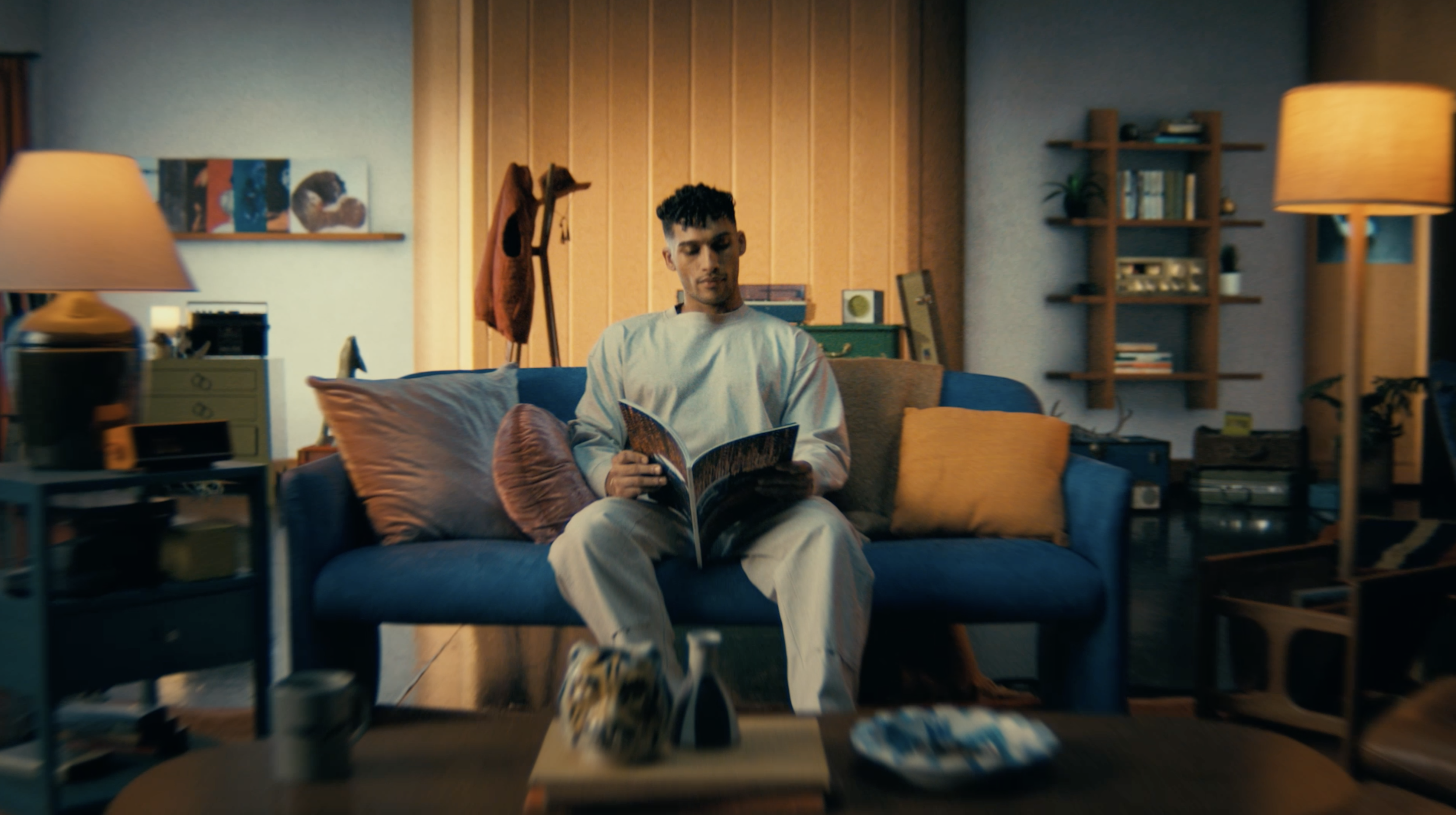 Man reading magazine on a blue sofa in his living room