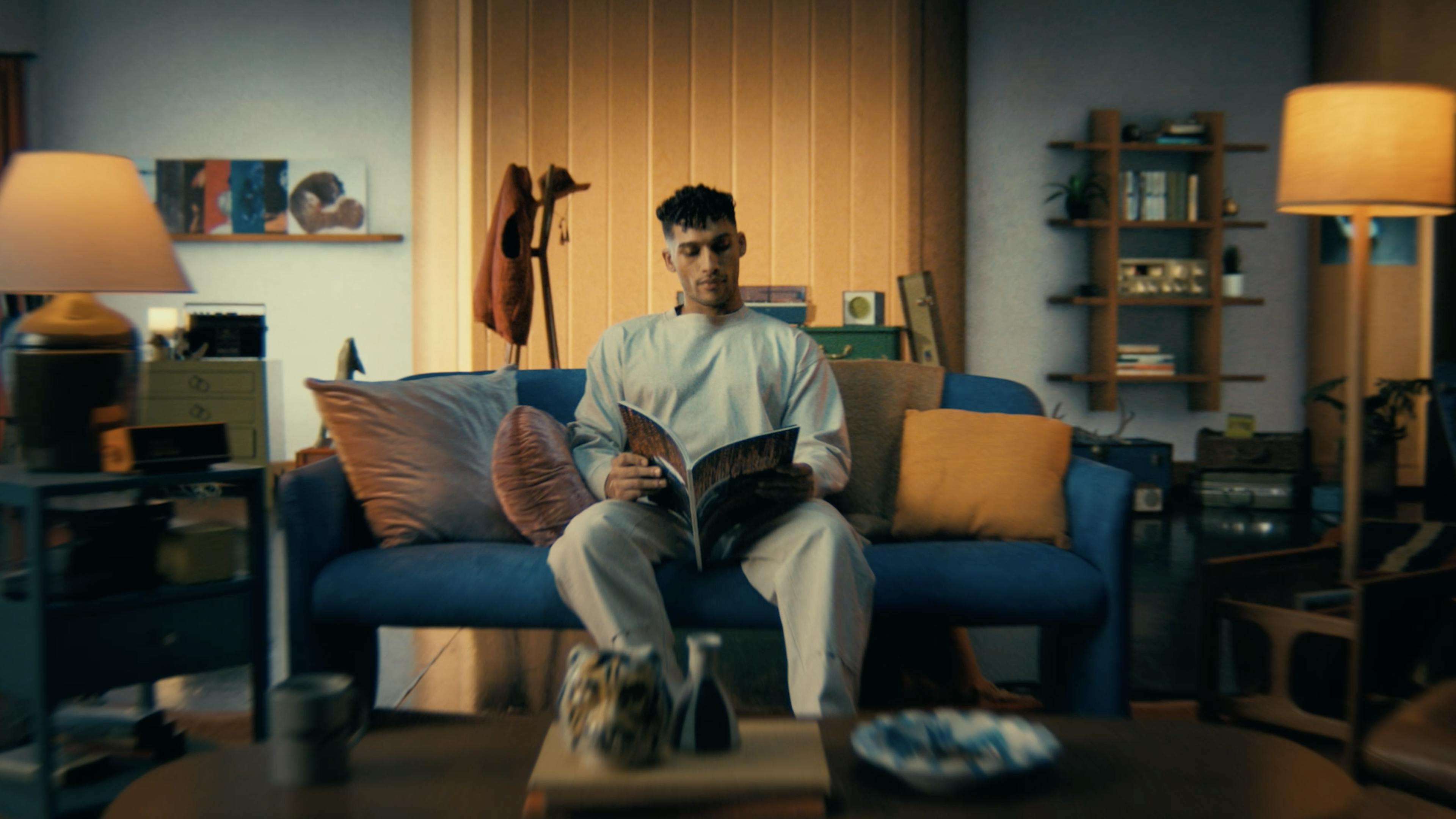 Man reading magazine on a blue sofa in his living room