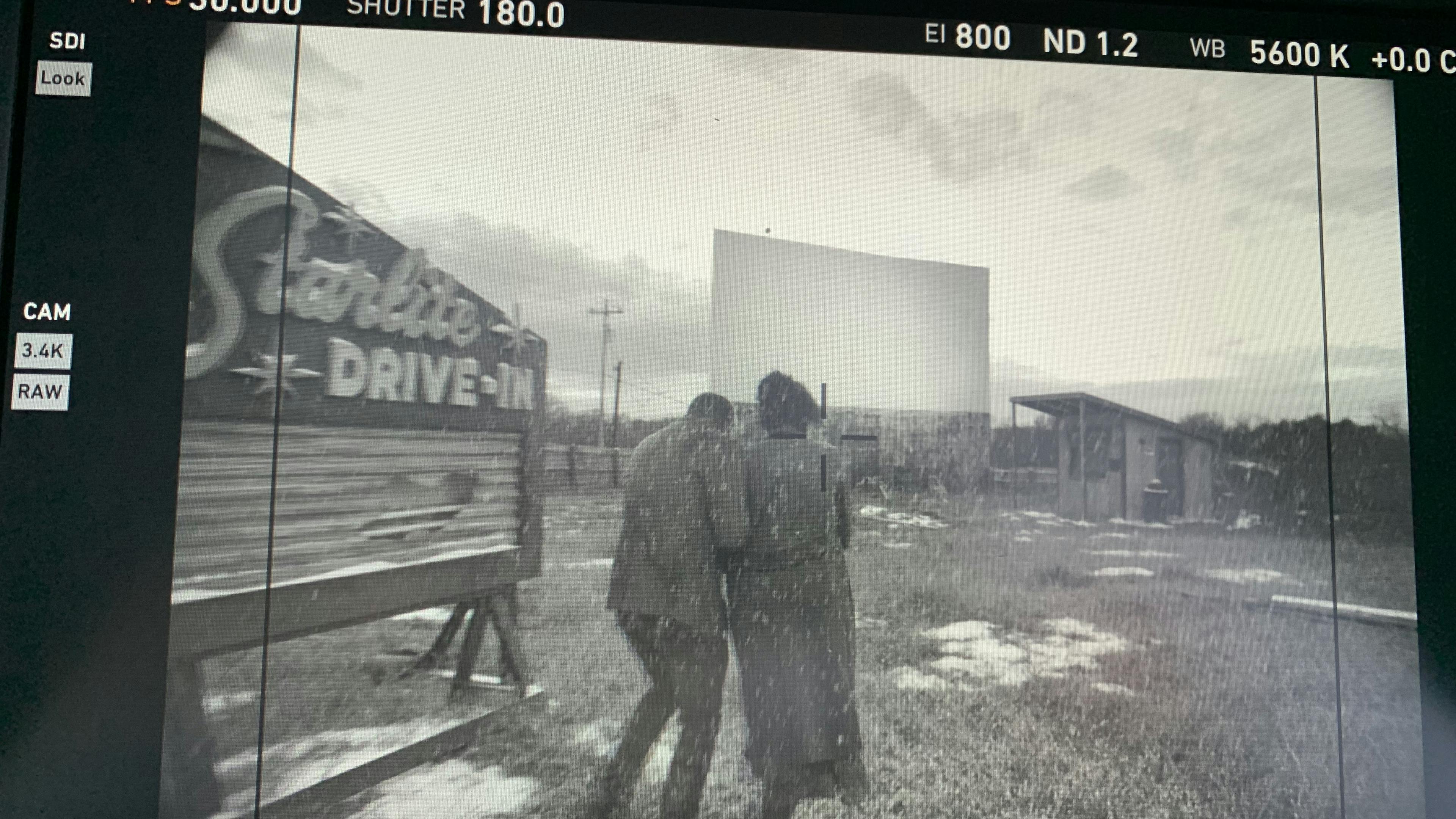 An image of a video camera screen showing two people walking into a drive-in movie theater
