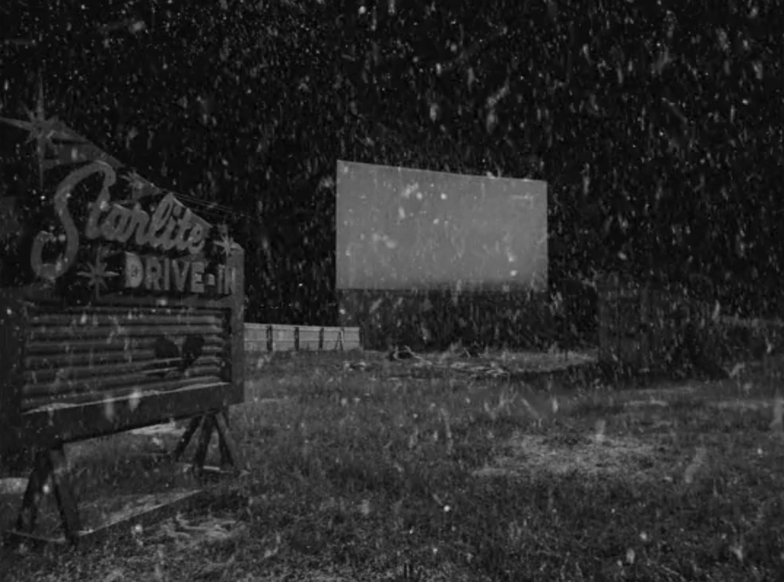 A black and white image of a snowy drive-in movie theater