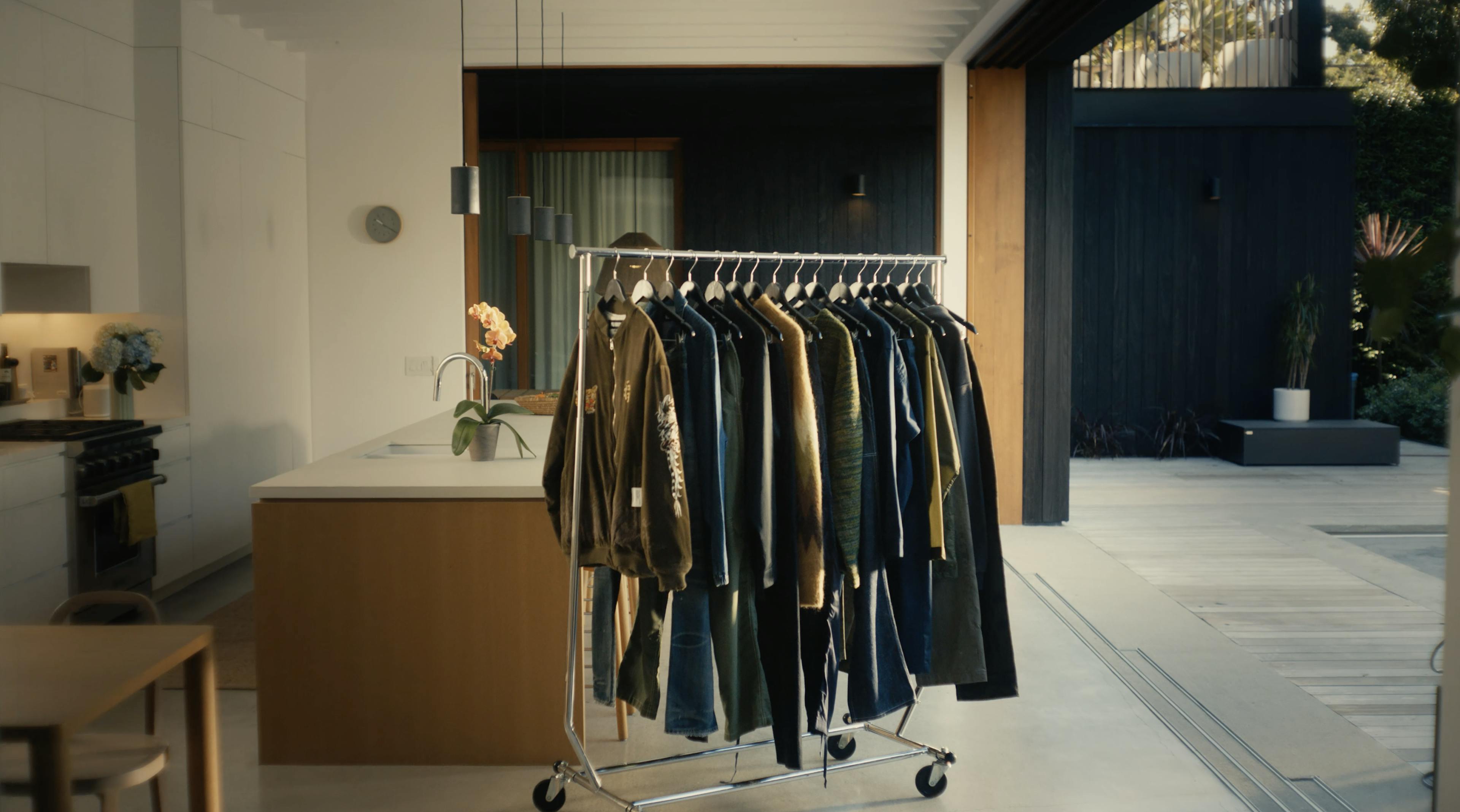 A clothing rack sits in a cleanly furnished space that opens to the outdoor patio