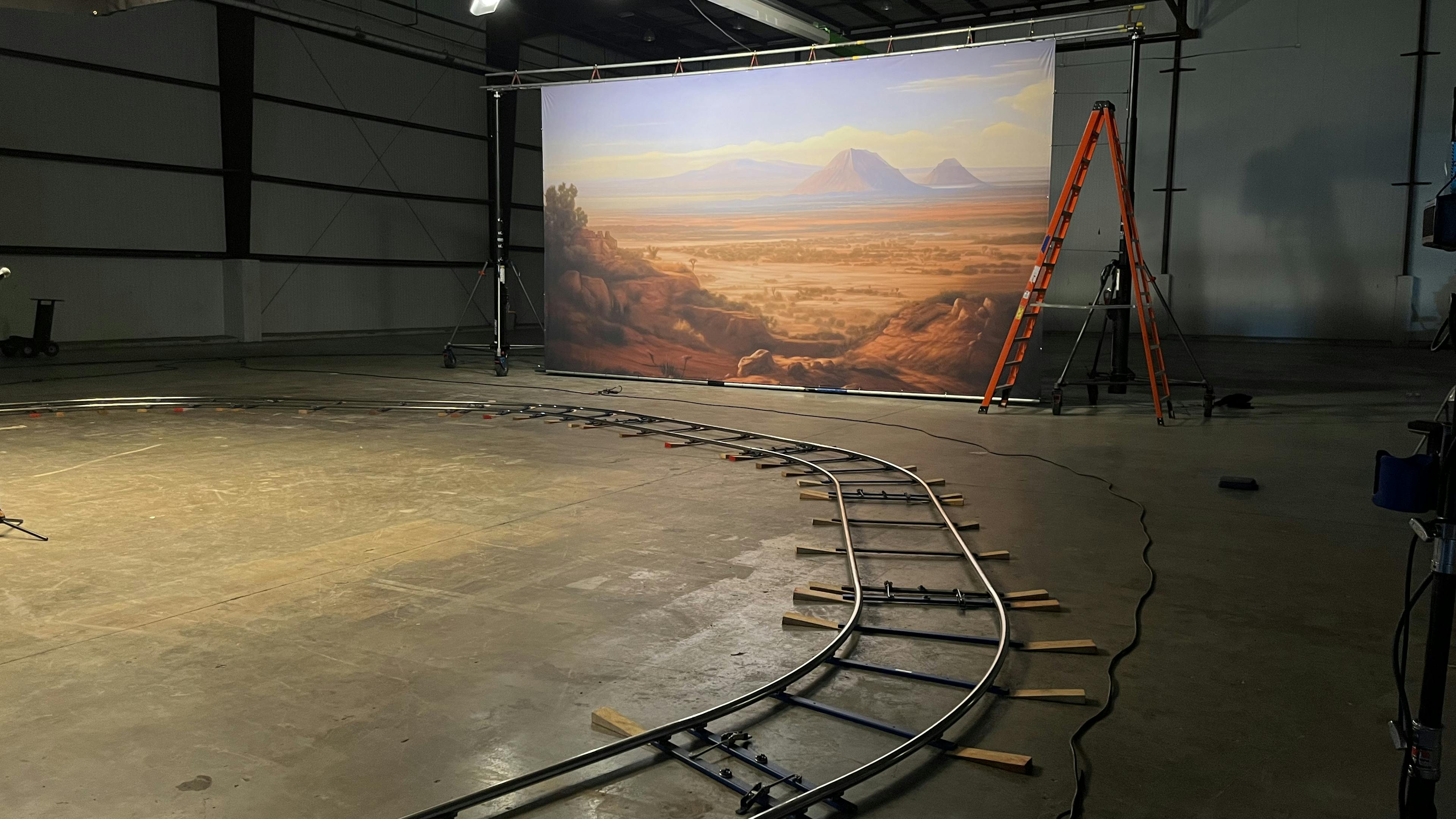 Small train tracks run through a studio with a backdrop of the desert