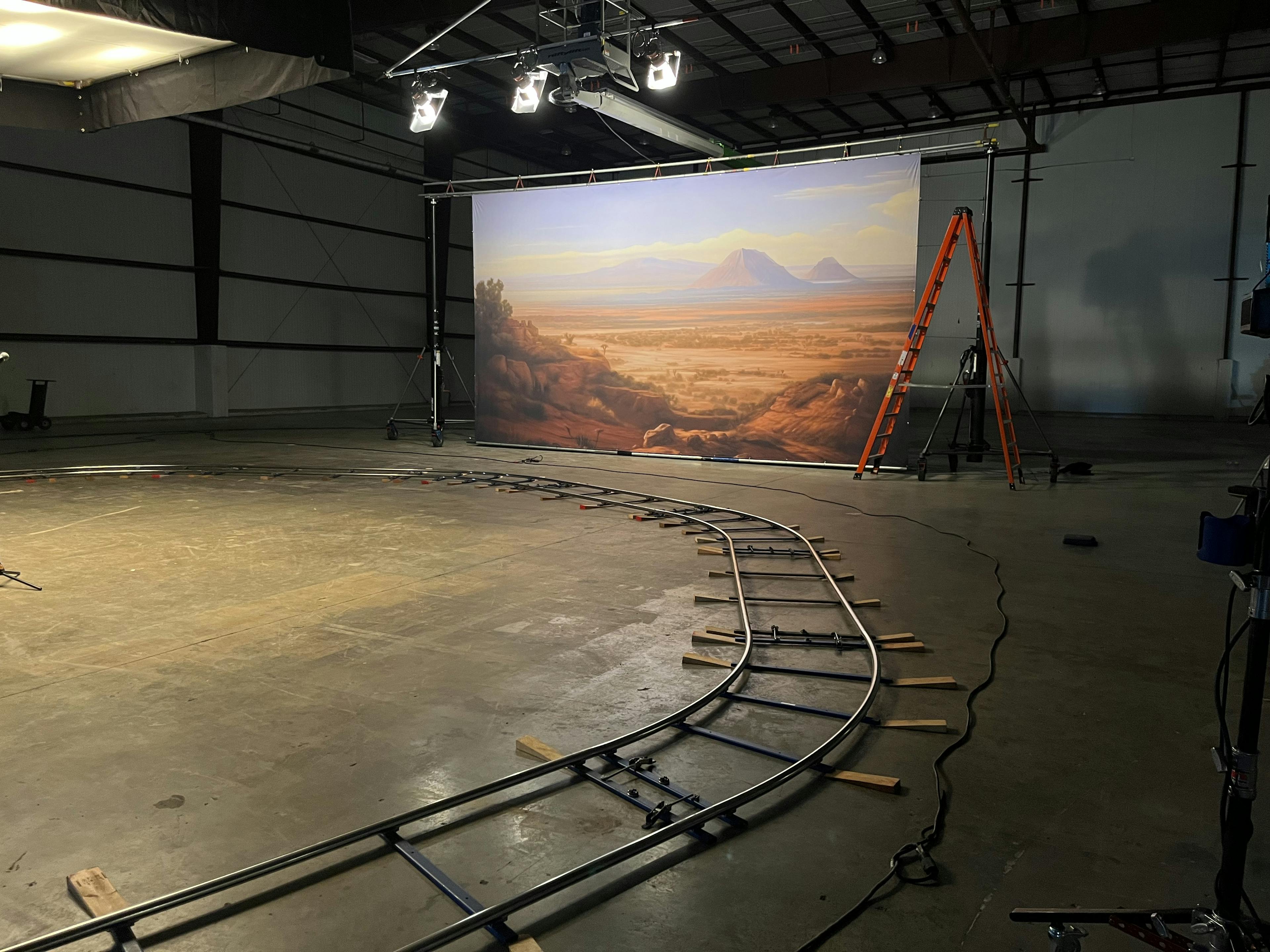 Small train tracks run through a studio with a backdrop of the desert