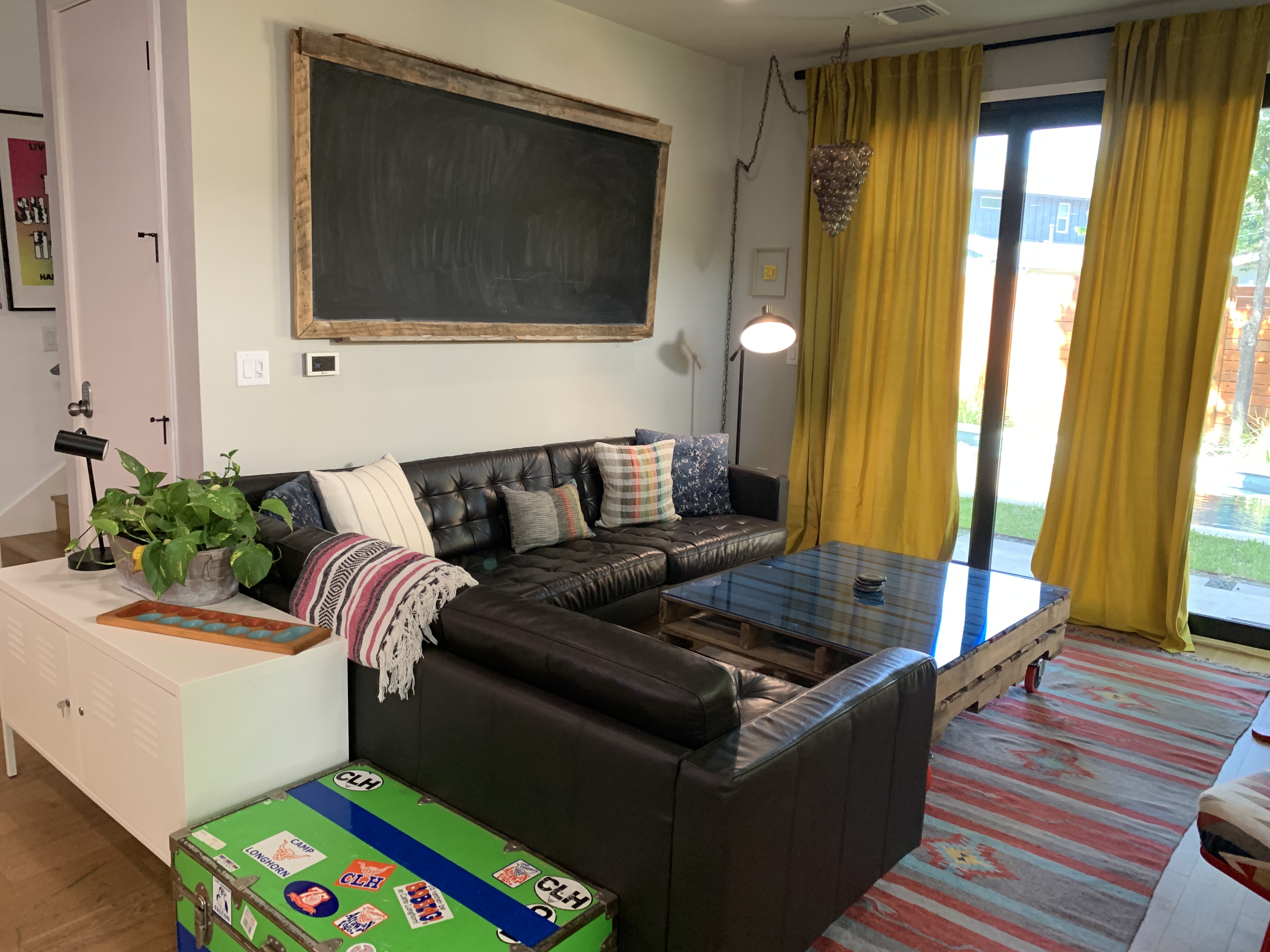 Black leather couches around a coffee table with a view of the backyard