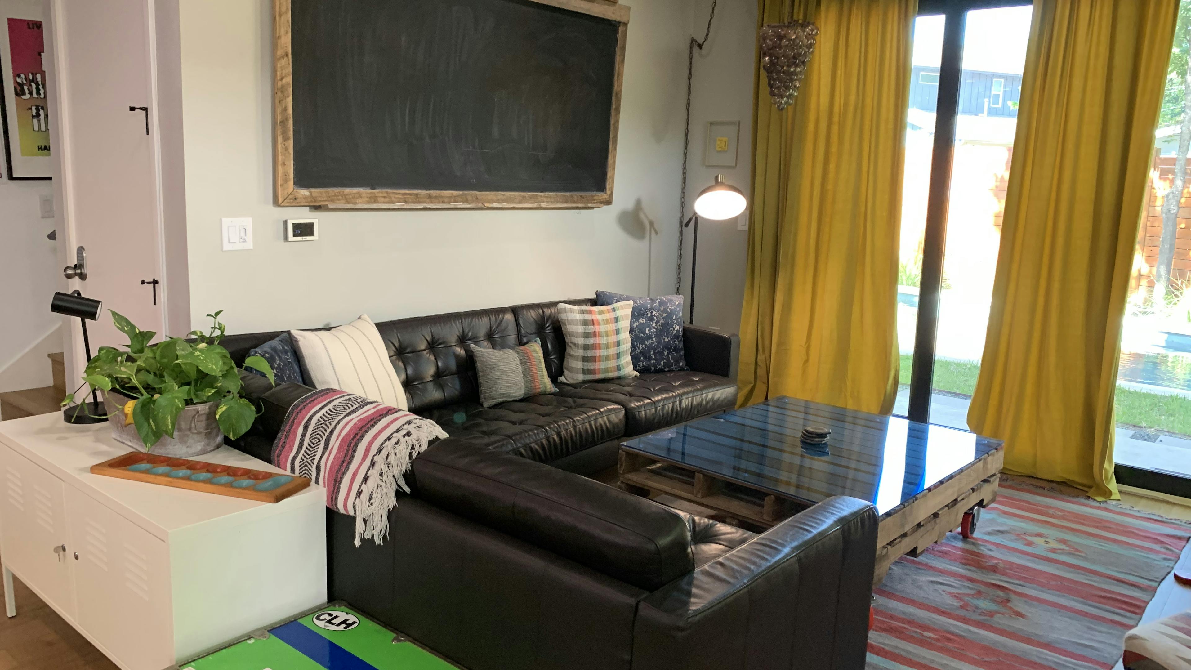 Black leather couches around a coffee table with a view of the backyard