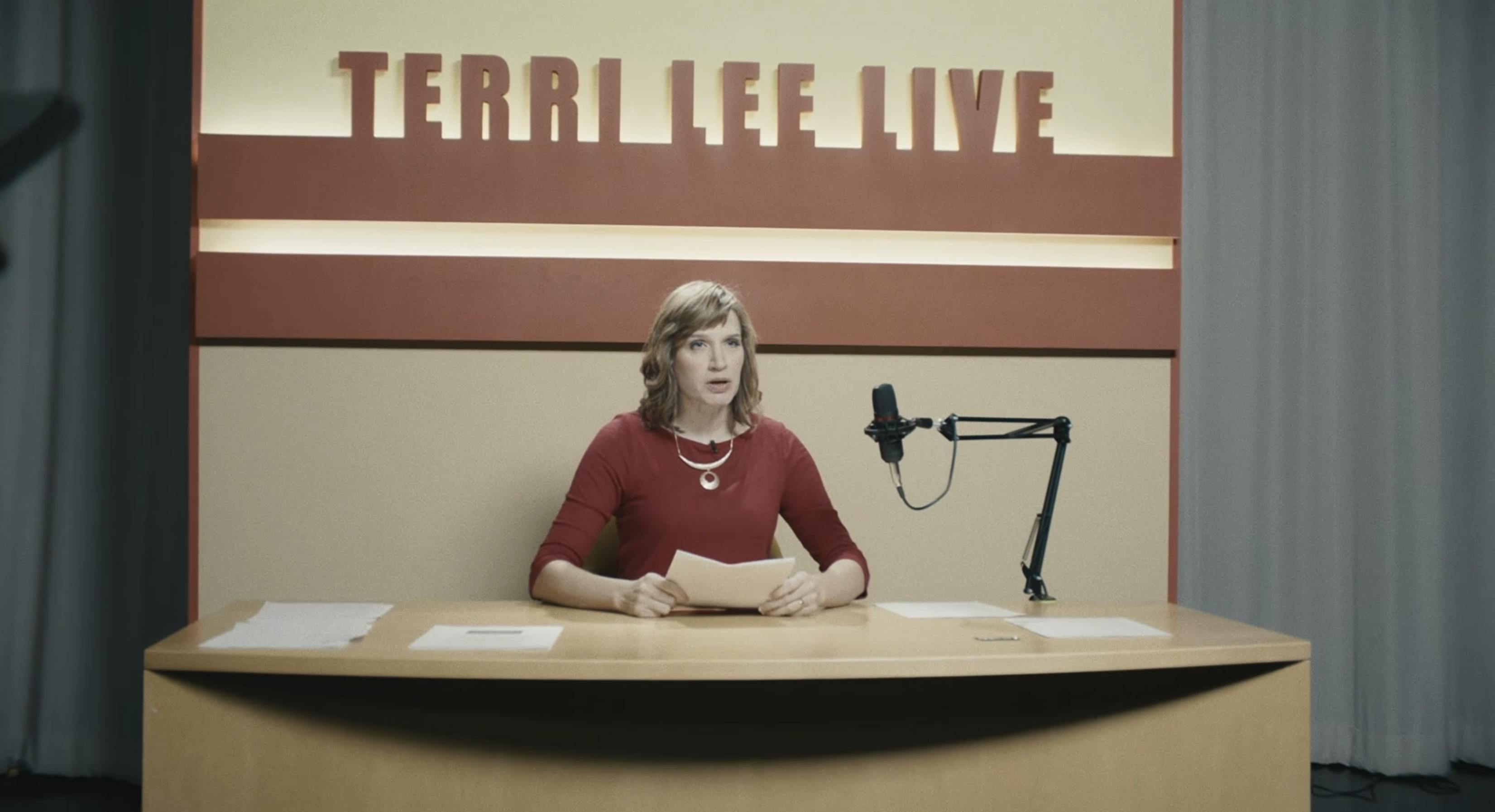 A newscaster in red with the text "Terri Lee Live" in the back