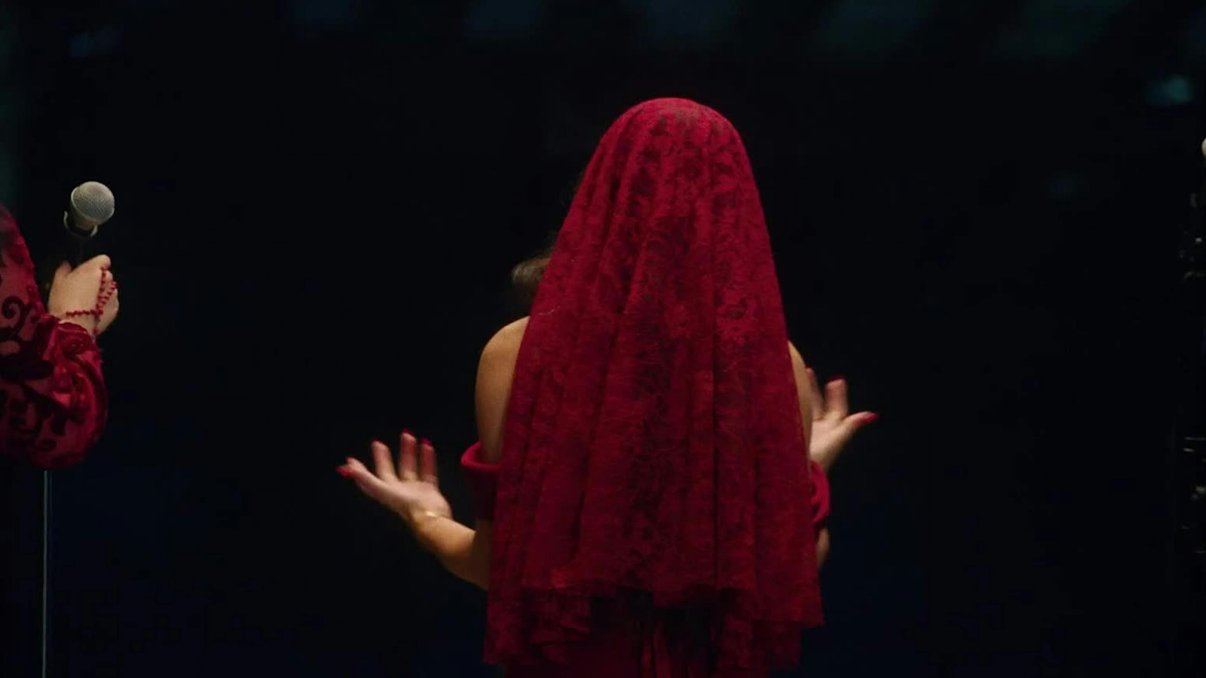 A woman in a red veil is shown from the back