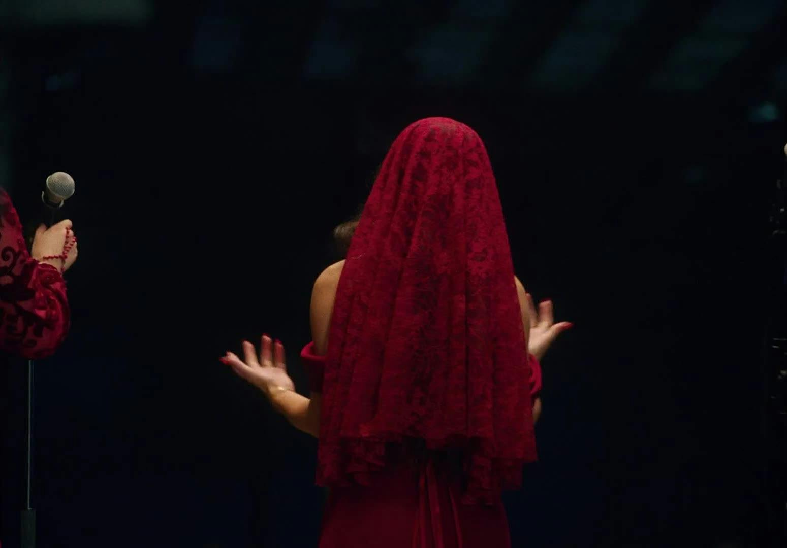 A woman in a red veil is shown from the back
