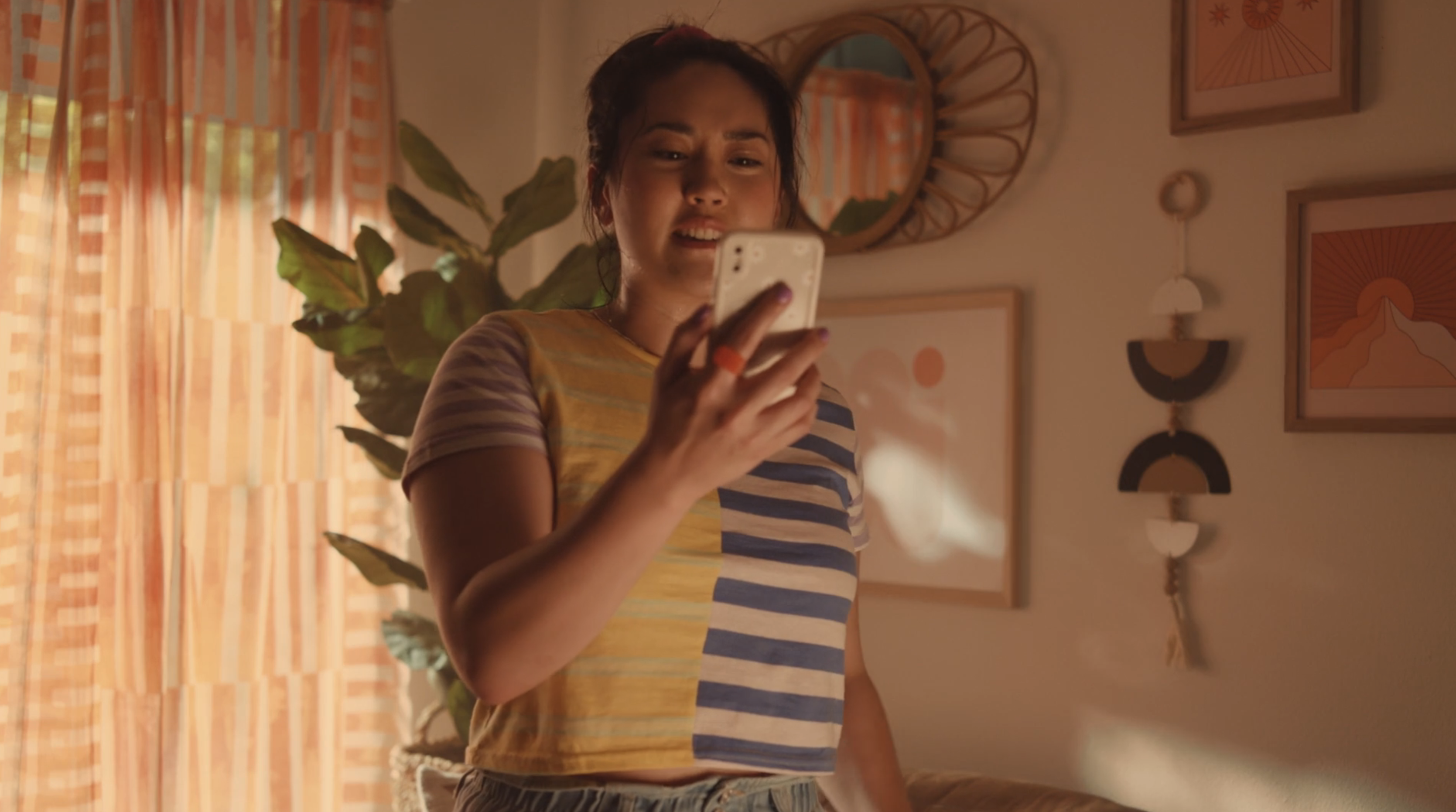 A woman looks at her phone in a sun-drenched room