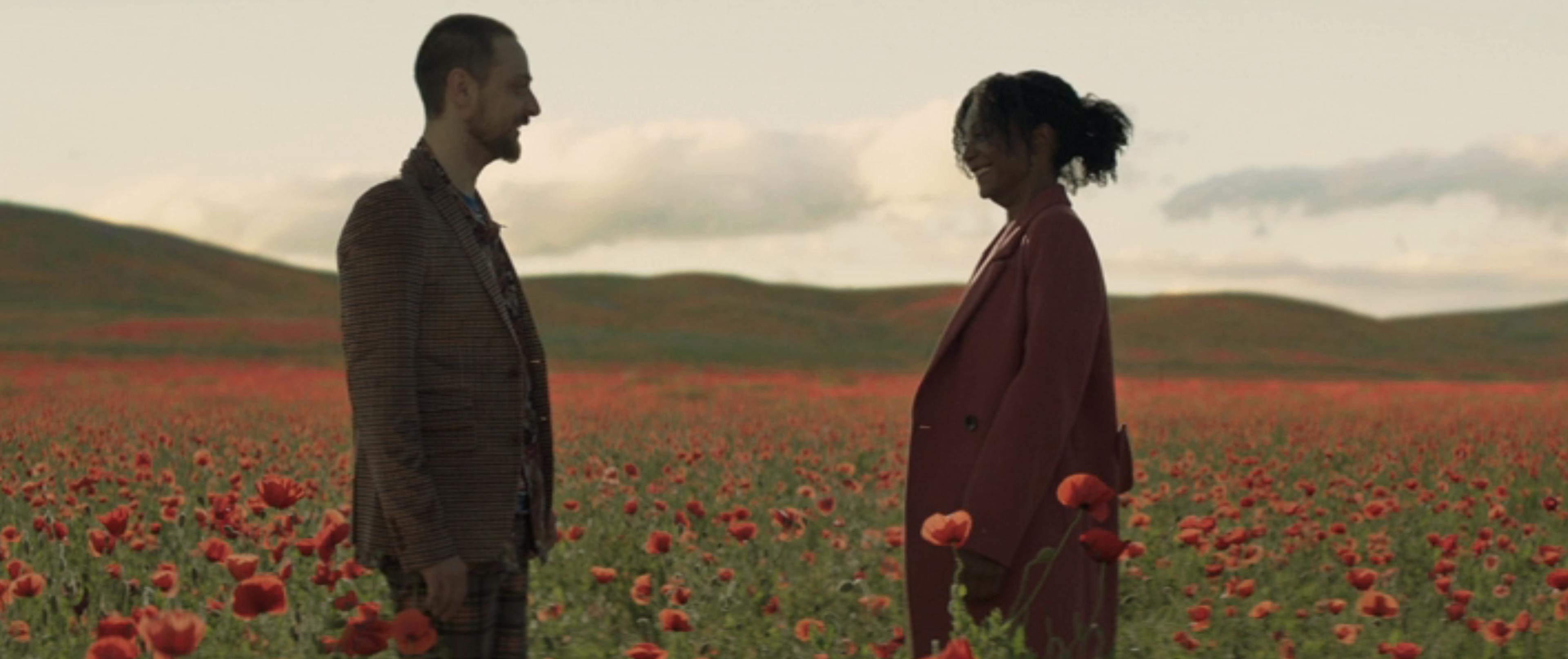 A man and woman face each other in a field of red poppies