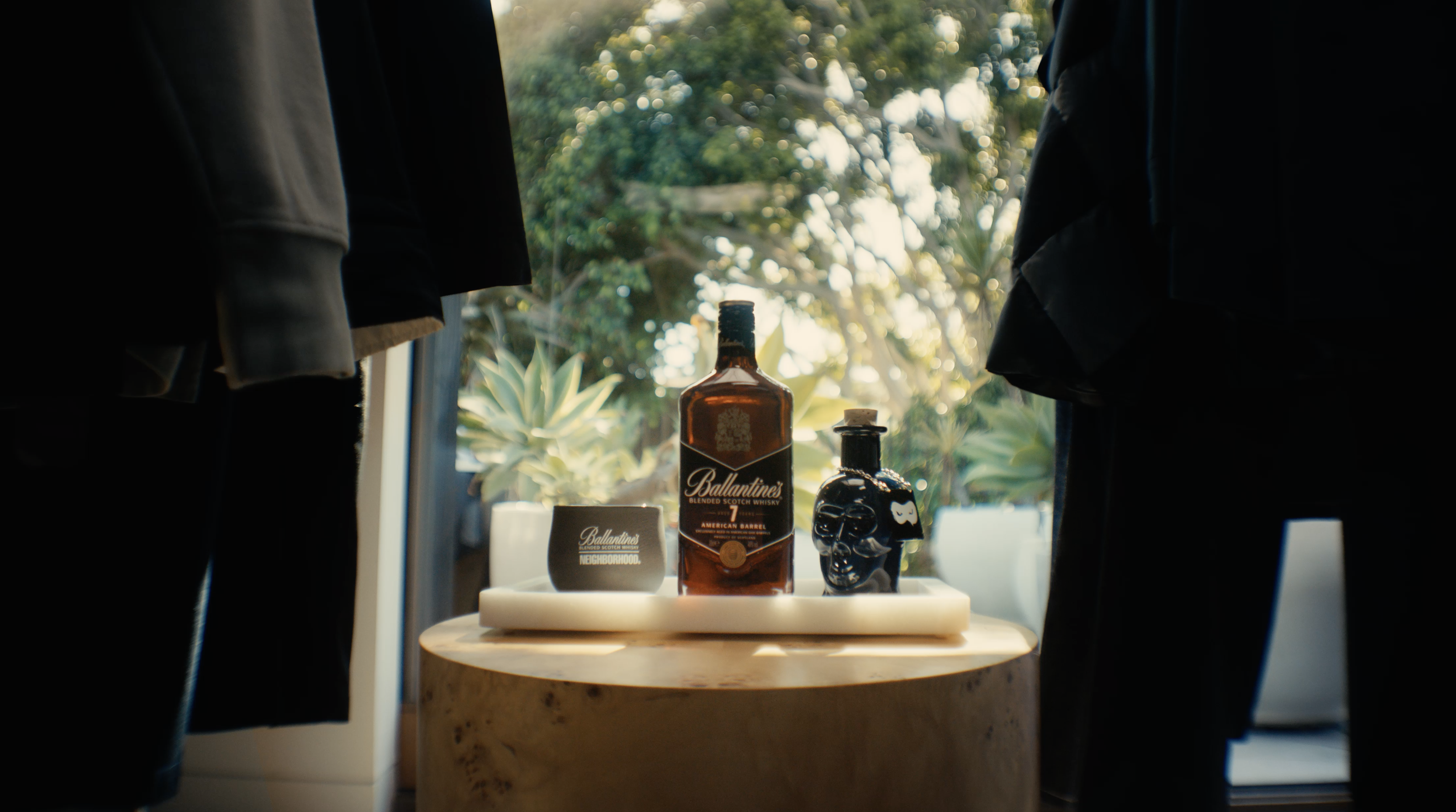 A bottle of Ballantine's whiskey sits on a tray on a wooden table