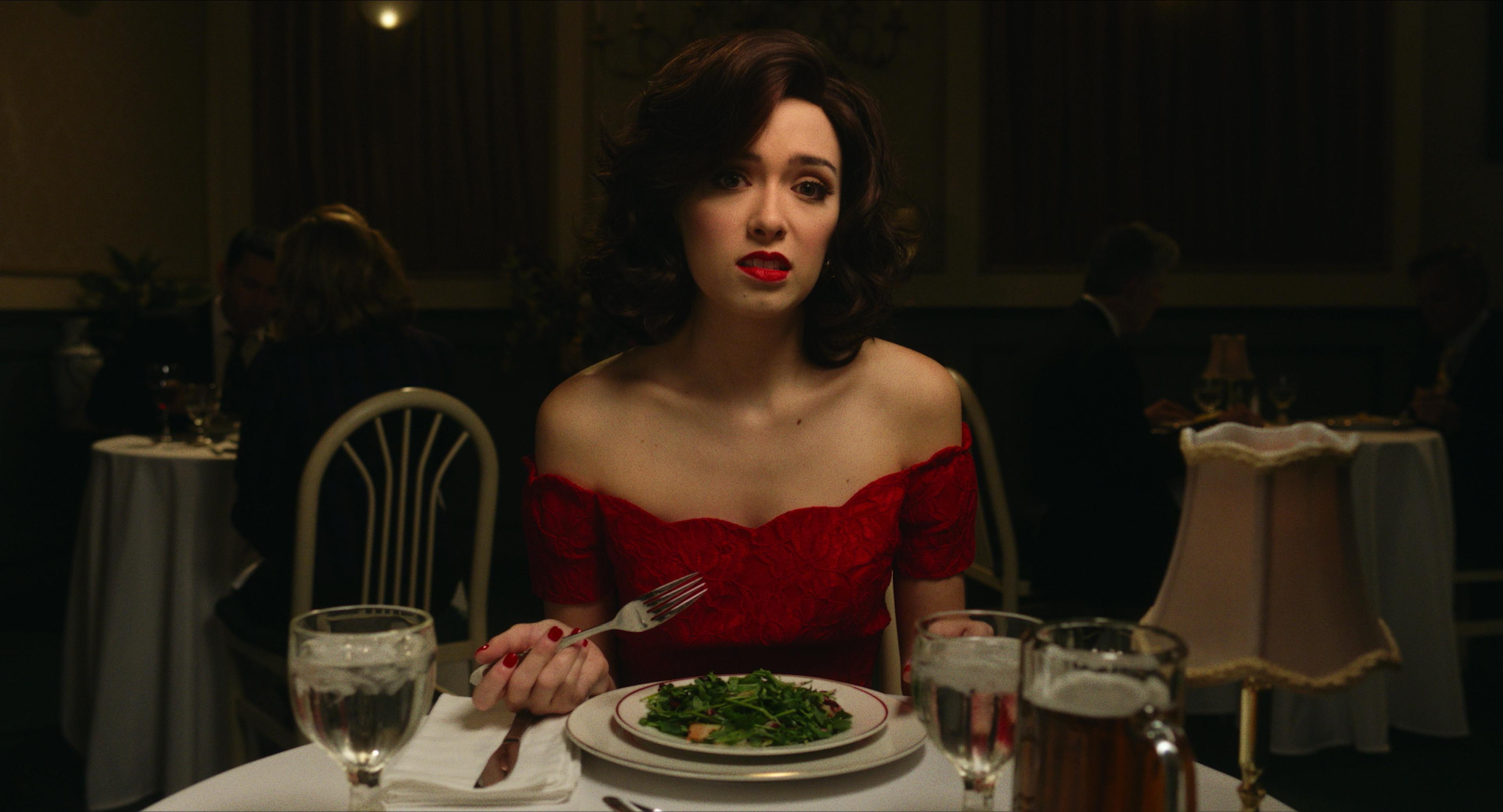 A woman in a red dress with makeup eats a salad
