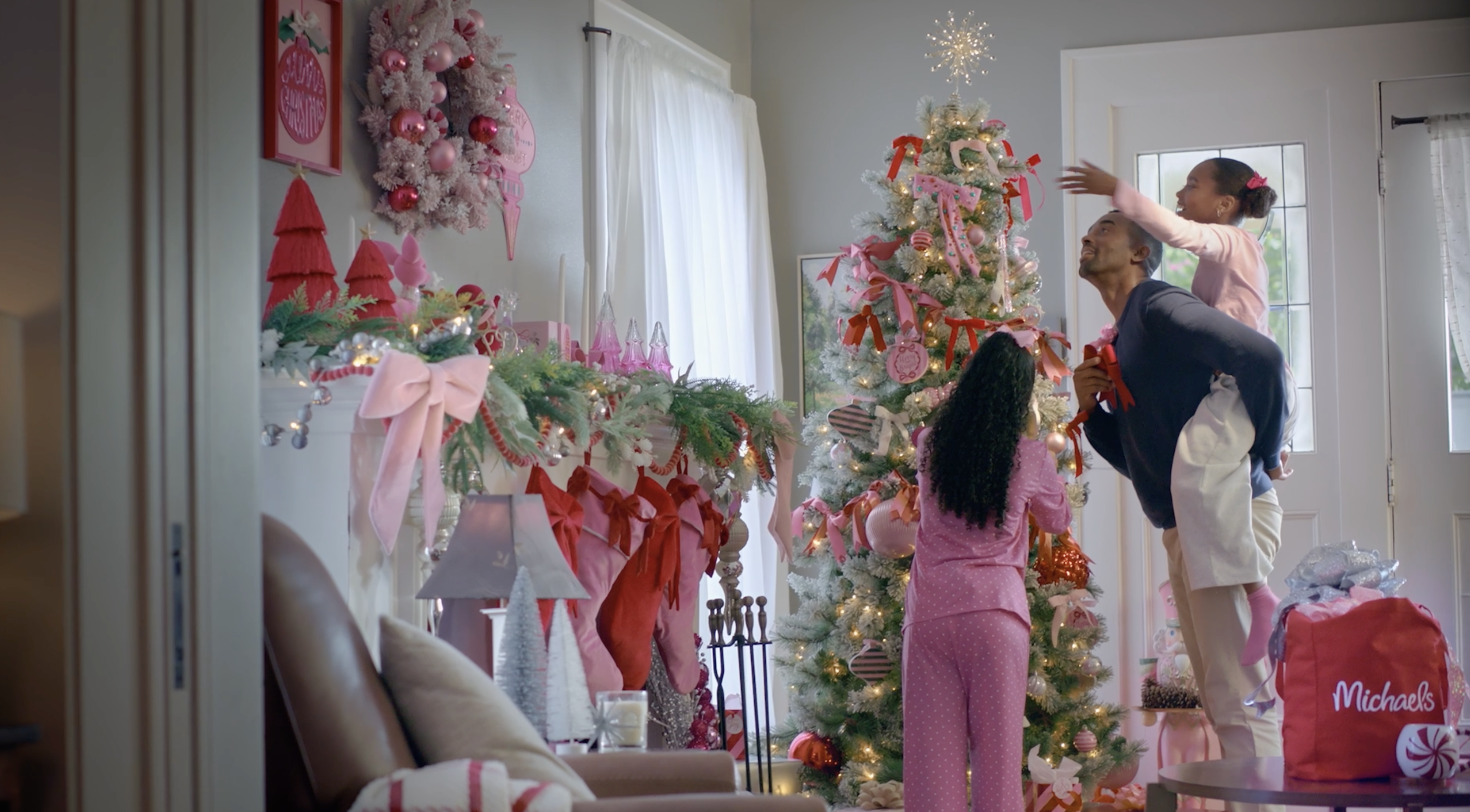 A father with 2 daughters decorating a pink christmas tree