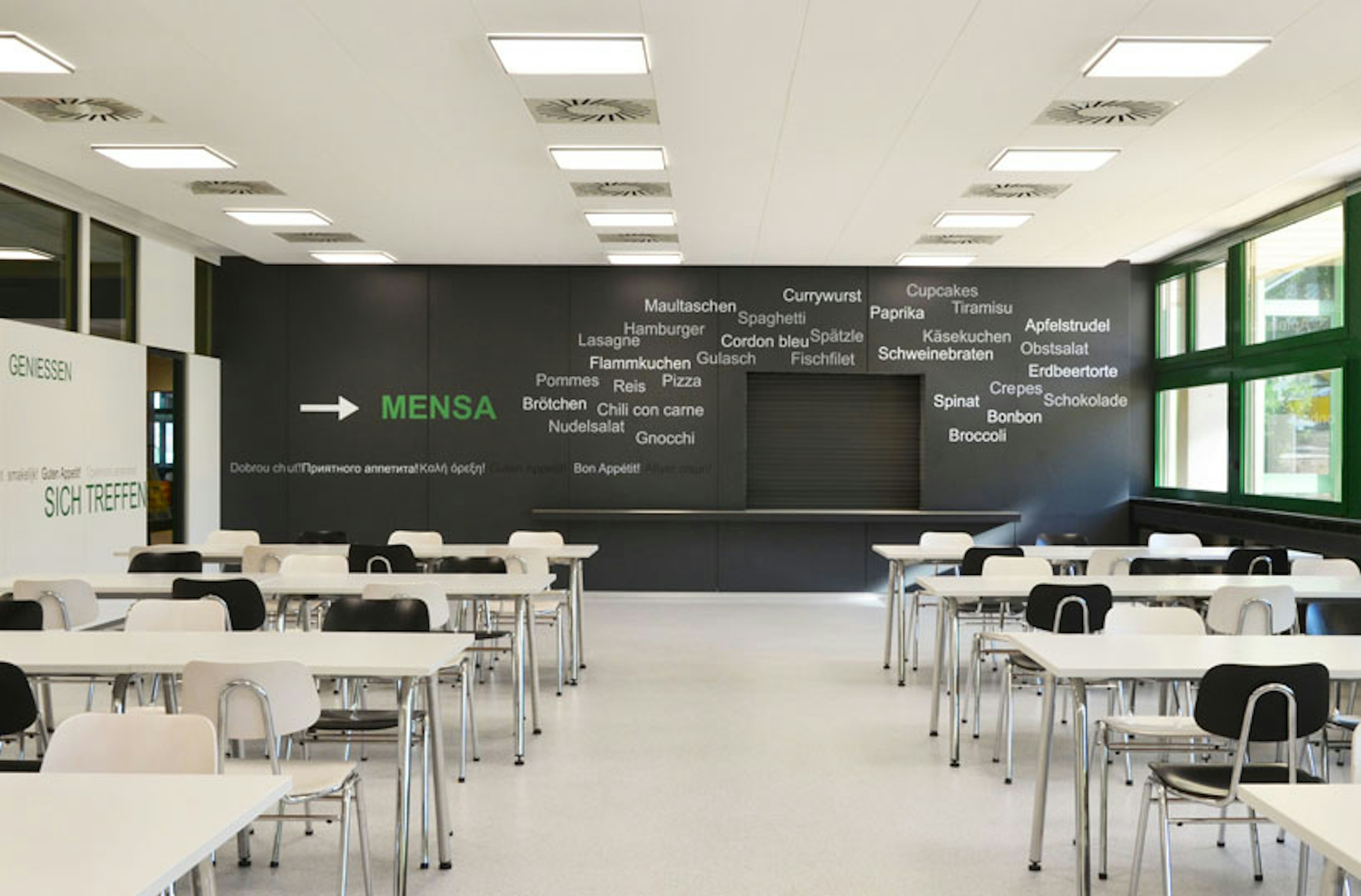 Sanierte Mensa des Kreisberufsschulzentrums Heilbronn mit moderner Wandgestaltung, weißen Tischen und schwarzen Stühlen, Umbau 2022.