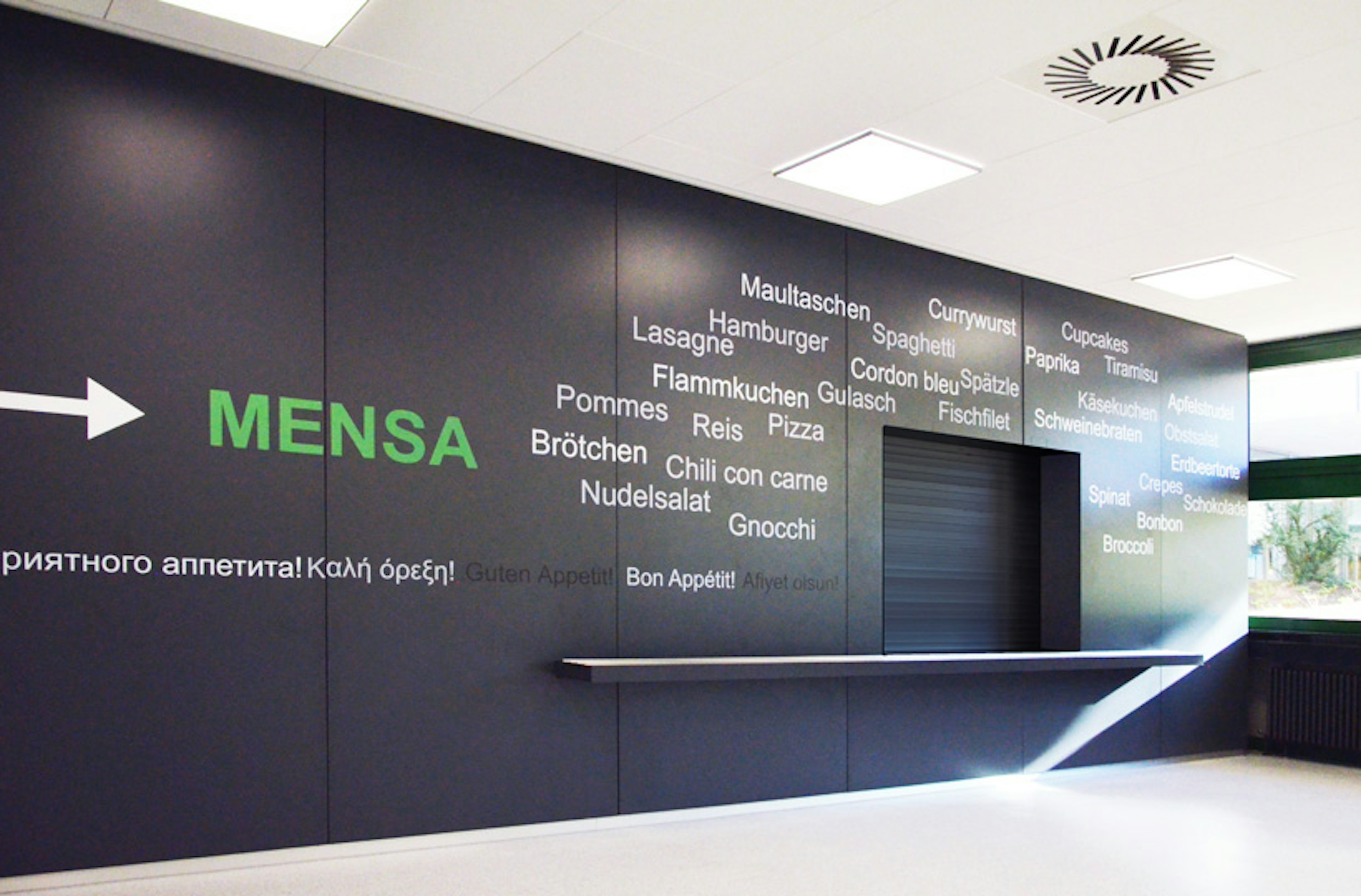 Ansicht der Essensausgabe mit schwarzer Wand und typografischer Gestaltung – neue Raumwirkung durch klare Linien und reduzierte Farben.