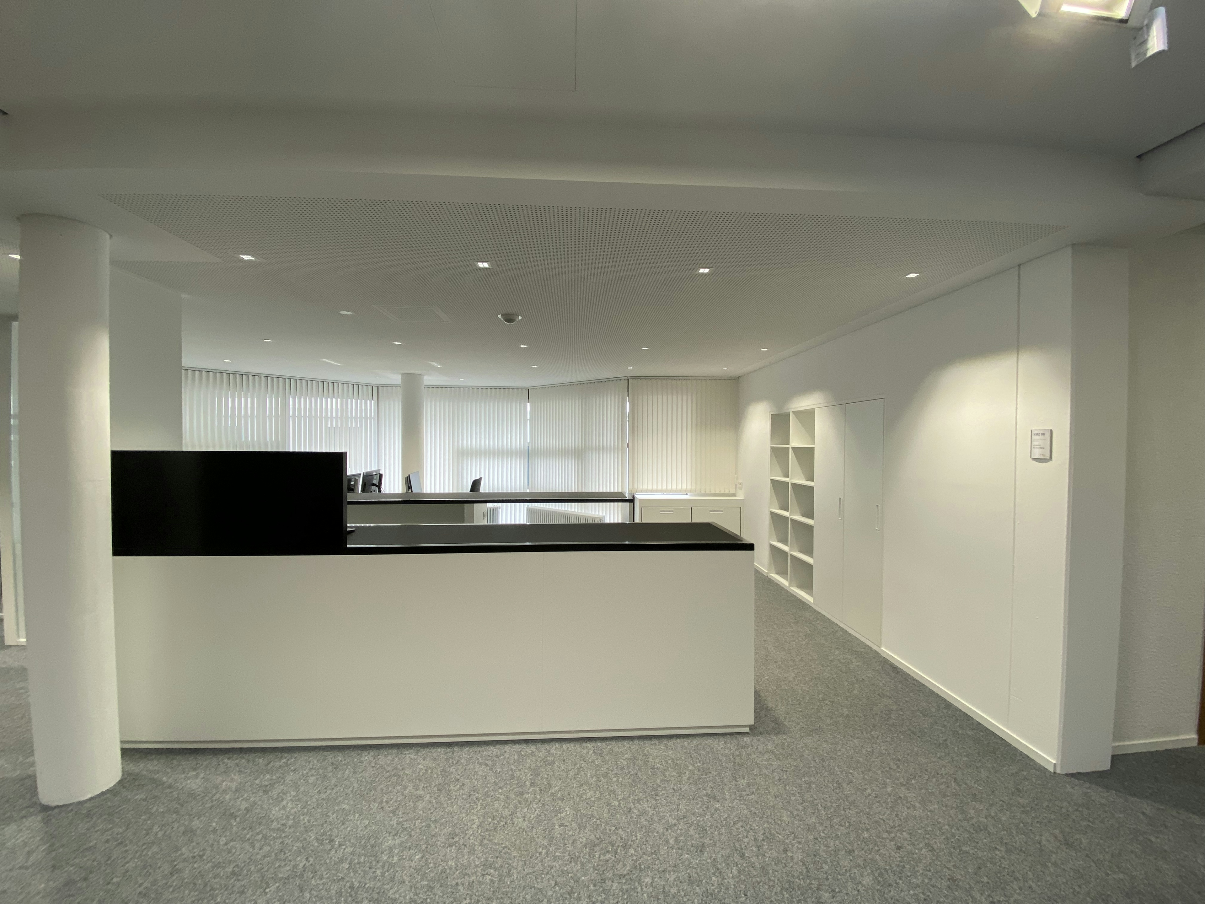 Empfangsbereich mit zwei Arbeitsplätzen, modernem Thekenmöbel und blickdichten Lamellenjalousien im Kreismedienzentrum Heilbronn.