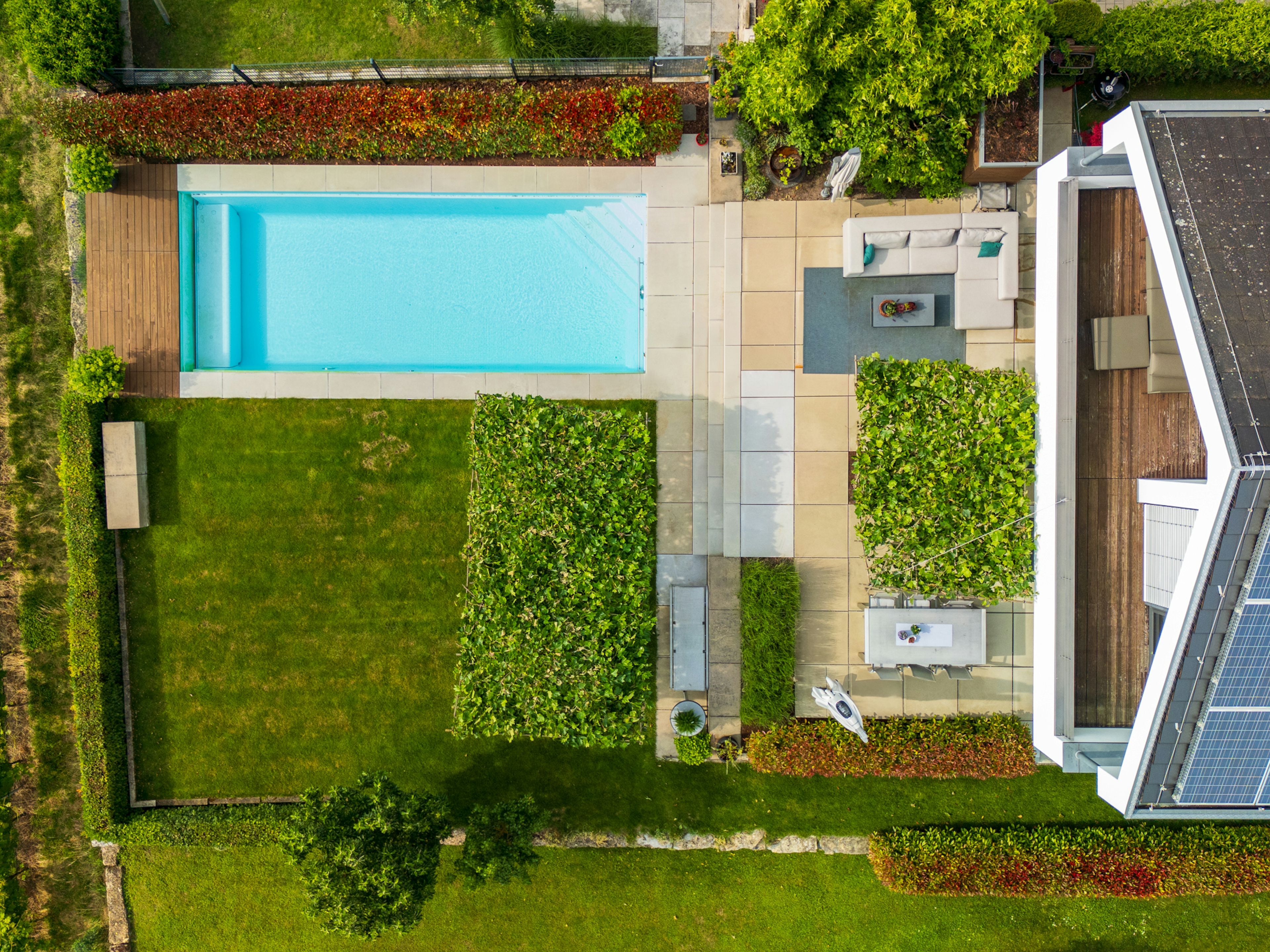 Drohnenbild moderner Außenanlage mit Pool, Garten und Sitzbereichen
