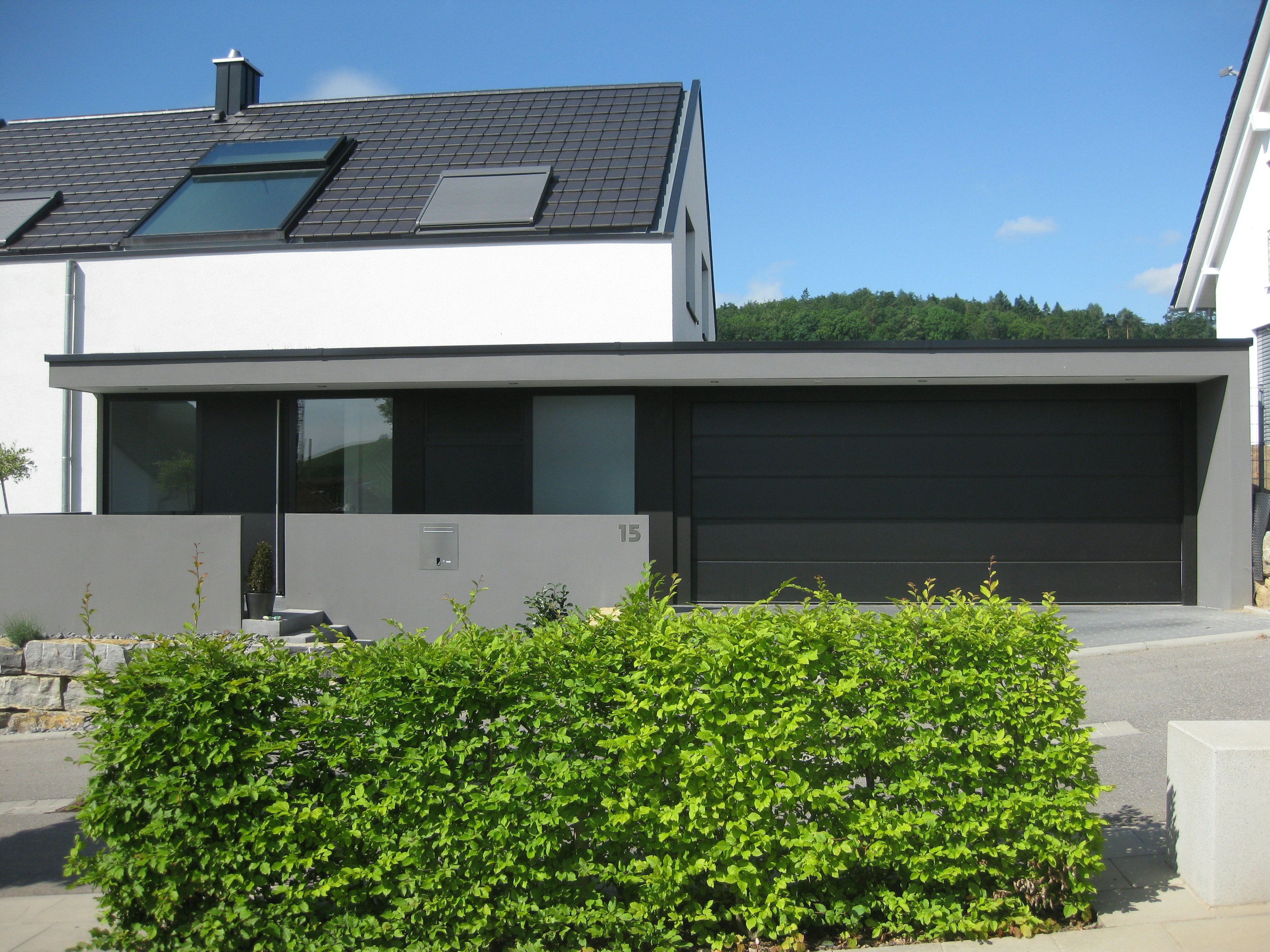 Blick auf den Eingangsbereich mit Sichtbetonelementen und harmonischer Verbindung von Architektur und Außenraumgestaltung.