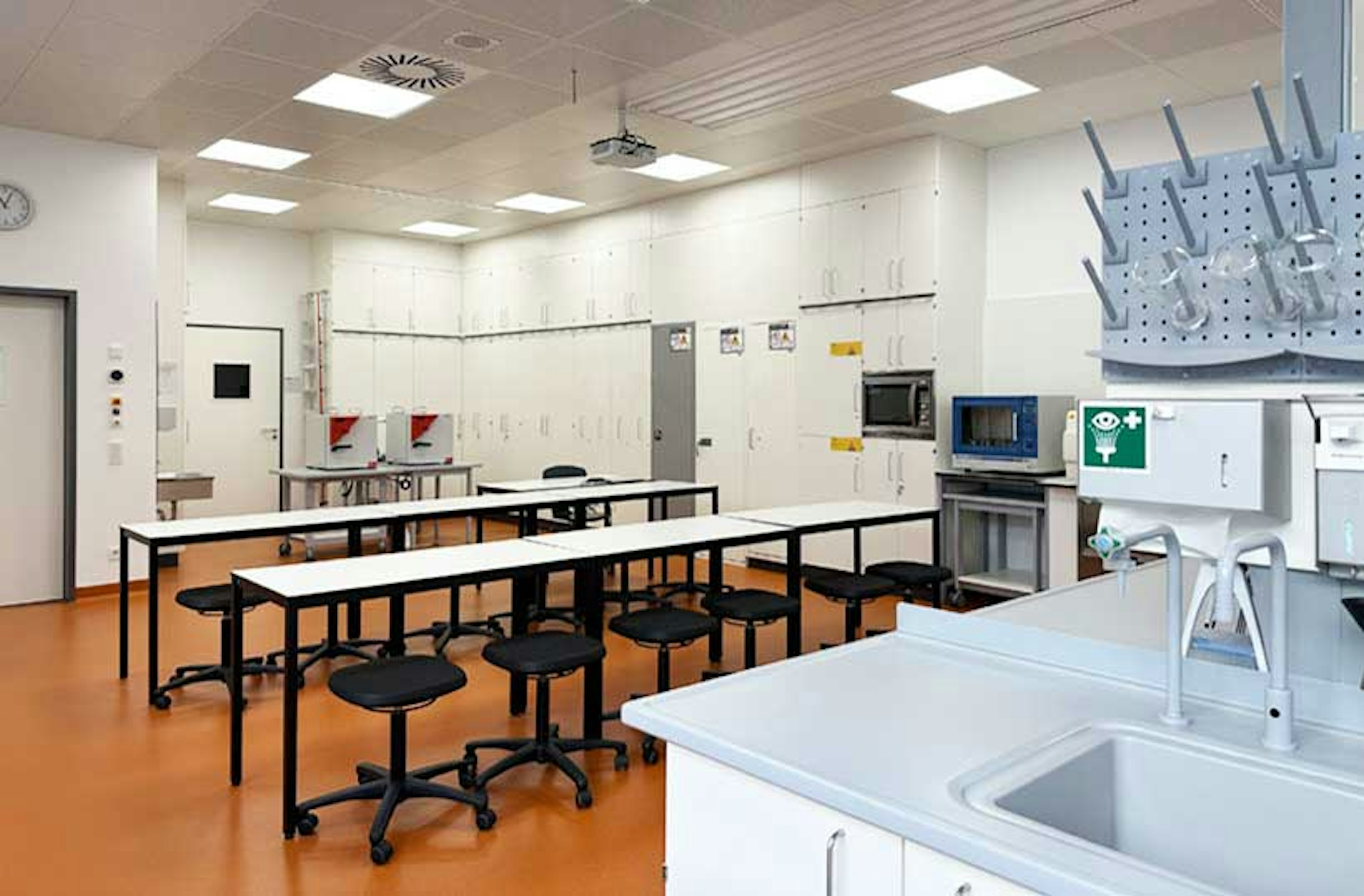 Blick auf den Schulungsbereich mit weißen Tischen, Stühlen und Wandregalen im Sprachlabor der Peter-Bruckmann-Schule.
