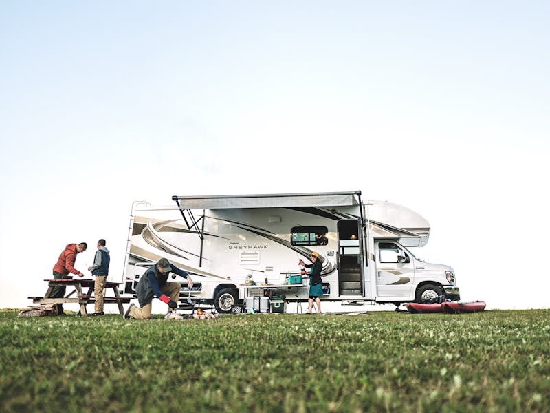 A family cooking dinner outside of a Jayco Greyhawk Class C RV