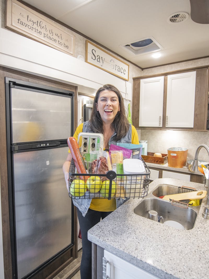 Chelsea Day holding a basket of food in the kitchen of her Highland Ridge RV