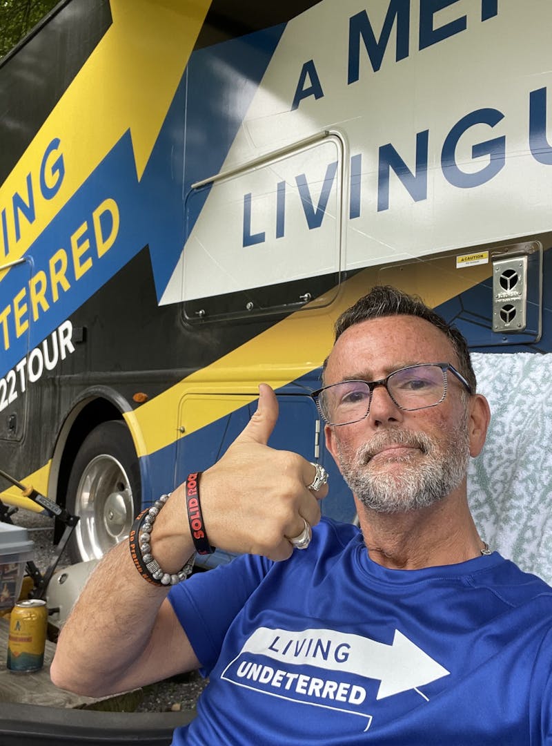 Jeff Johnston sitting in front of his Class A Motorhome with a thumbs up