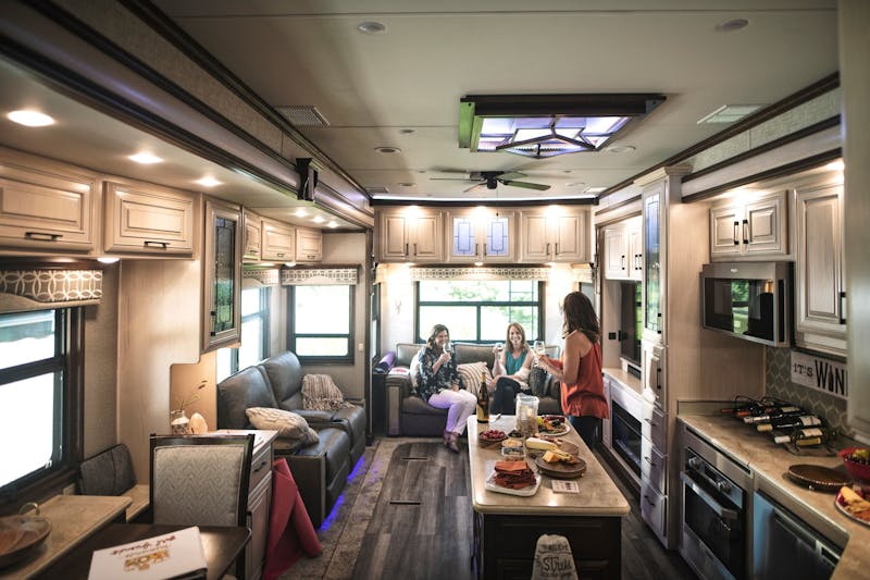 Three women enjoying wine inside of a DRV Luxury Suites RV