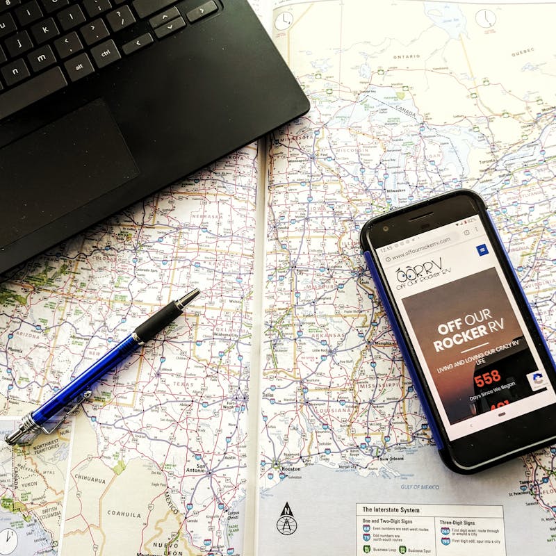 A phone and a laptop on top of a paper map of the United States.