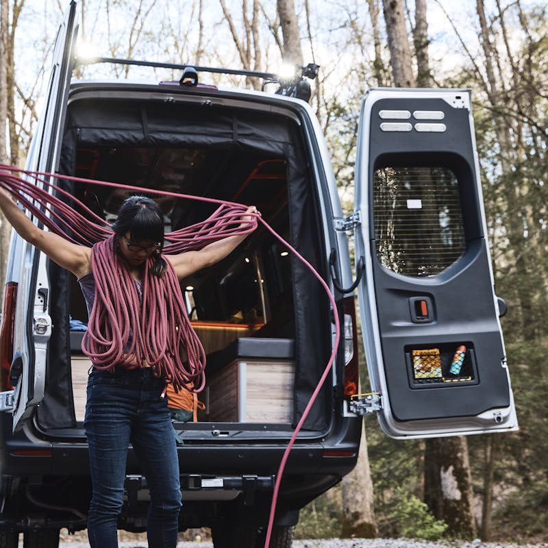 Kathy Karlo prepping climbing gear outside of an Airstream camper van