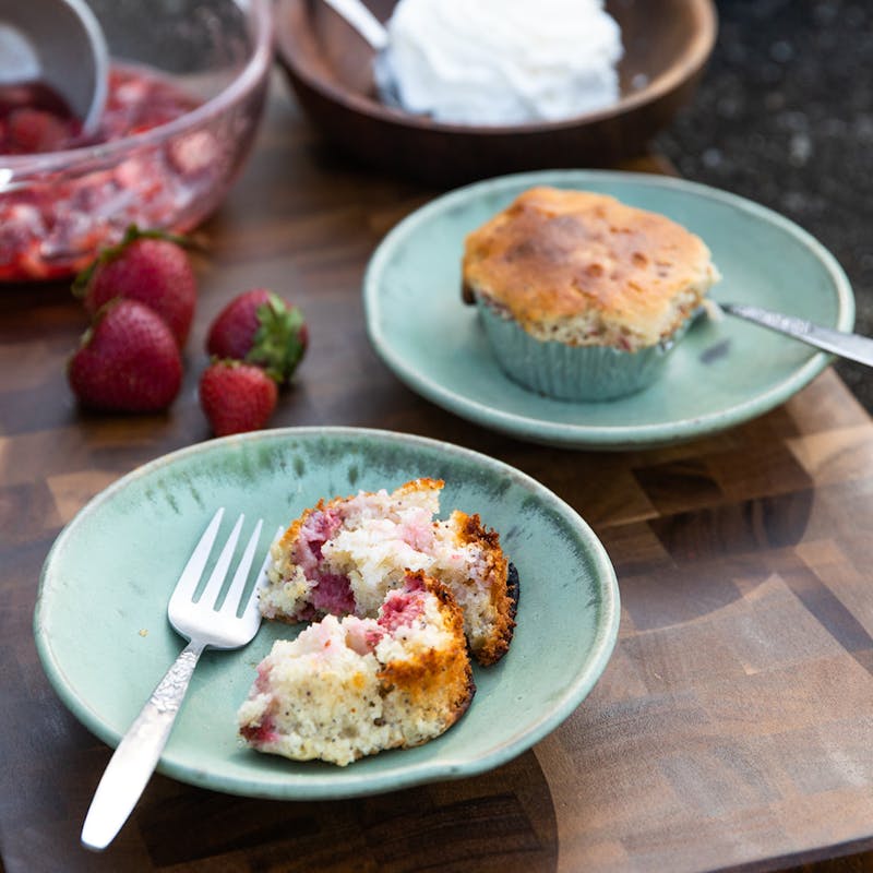 A strawberry corn muffin broken apart on a plate.