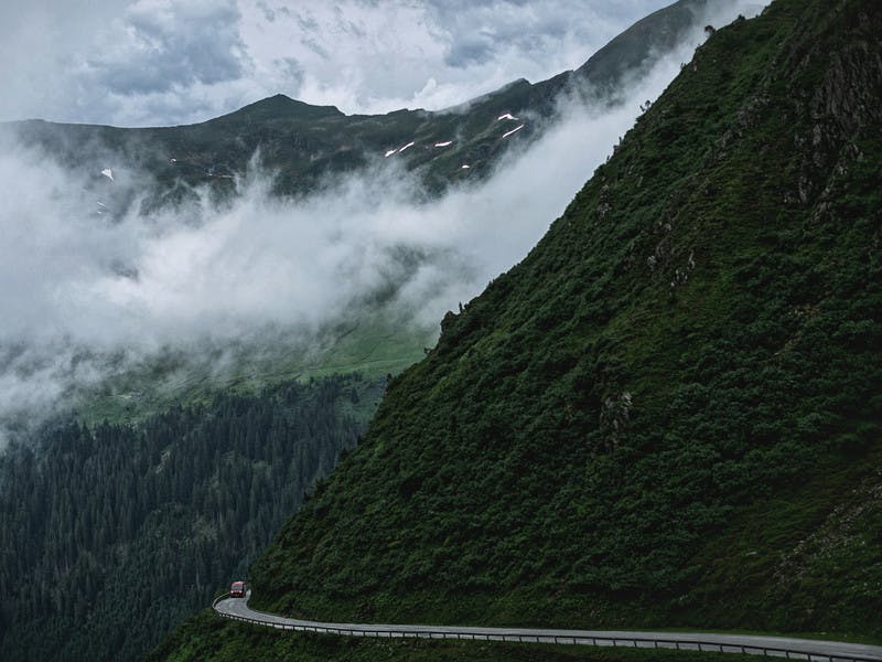 Class B RV drives through through foggy mountain road.