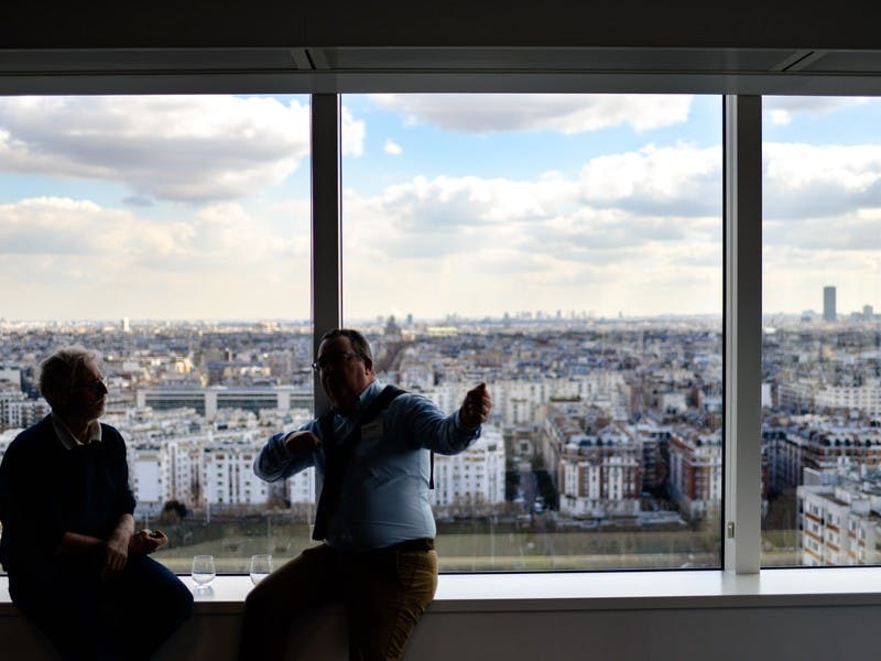 Two men in discussion, sitting in sky scraper building overlooking city