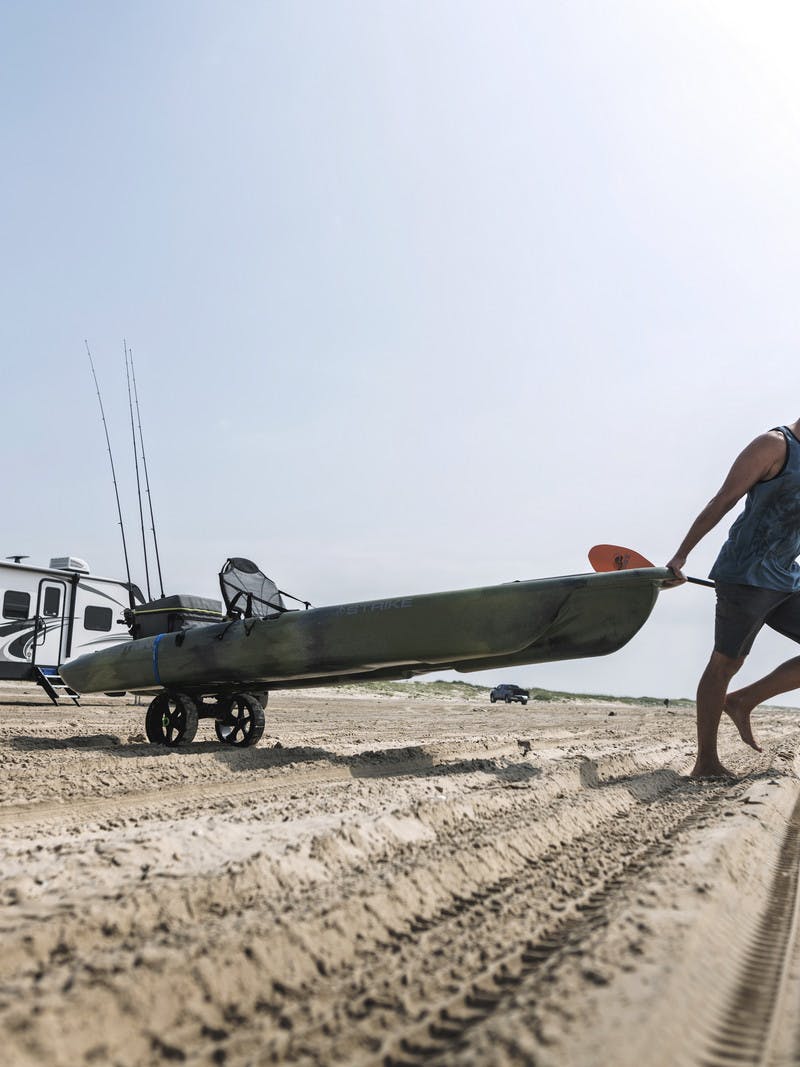 Robert Fields pulls his kayak across a sandy beach that he's unloaded from this Cougar travel trailer.