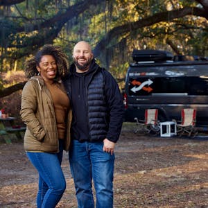 Gabe and Rocio Rivero smiling for a portrait in front of their Thor Motor Coach Sequence Class B Camper Van