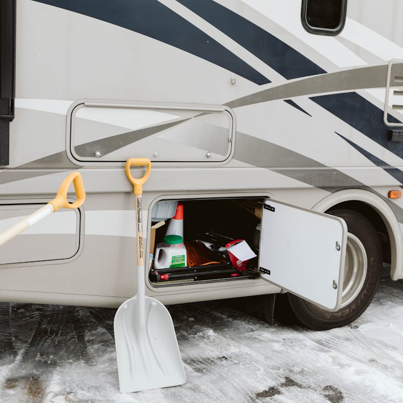 Storing snow shovels in an exterior RV cubby.