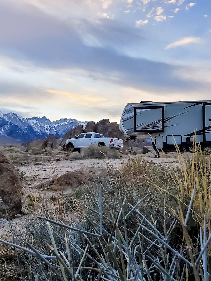 A toy hauler RV parked at the foot of snow covered mountains.