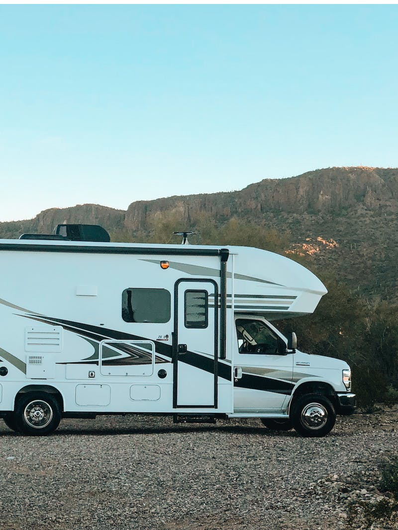Natalie Allen climbing on top of Entegra Class C RV in the desert.