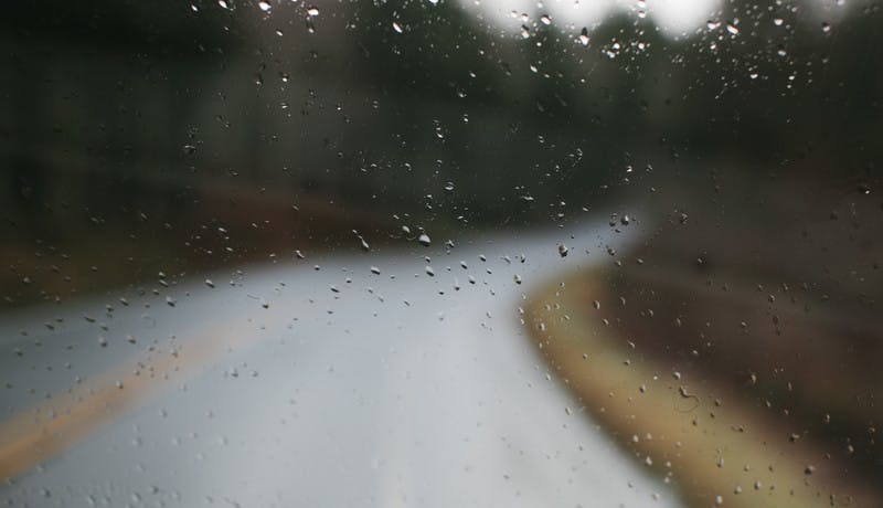 Water droplets on an RV window with a blurry road in the background.