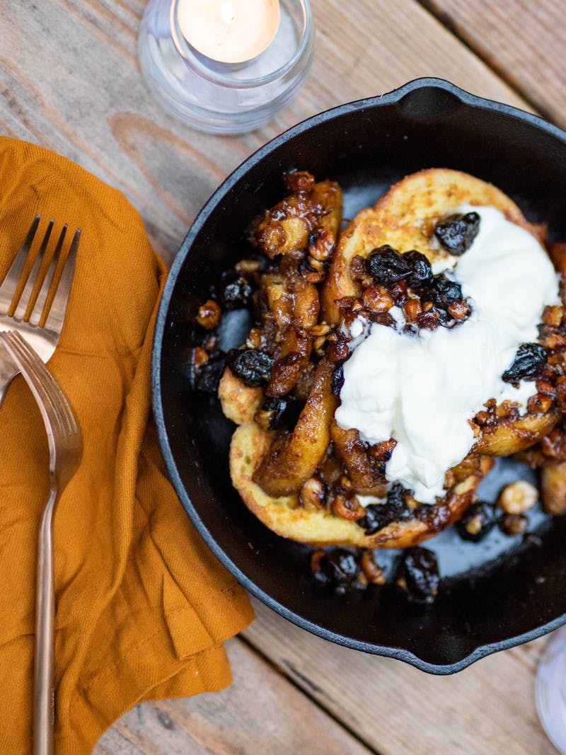 Campfire hazelnut cherry bananas foster with french toast and whipped cream in a pan, ready to eat.