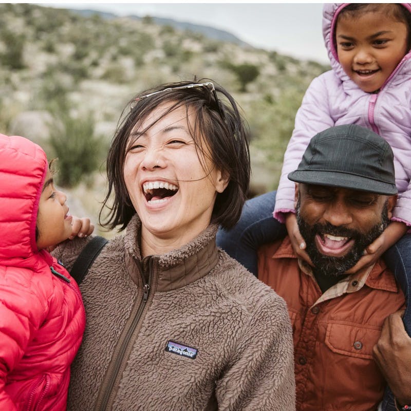 Close up of laughing family, Asian American woman and African American man, with two kids in puffy jackets and hoods.