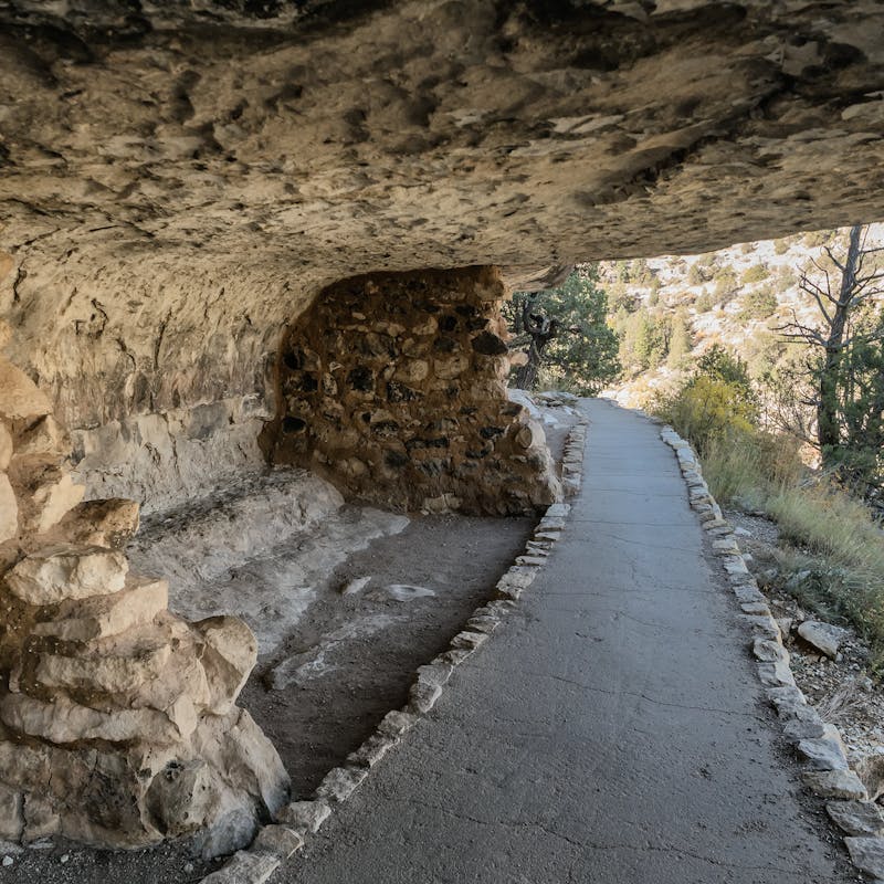 Caves, tunnels and caverns along the side of a desert mountain with green brush